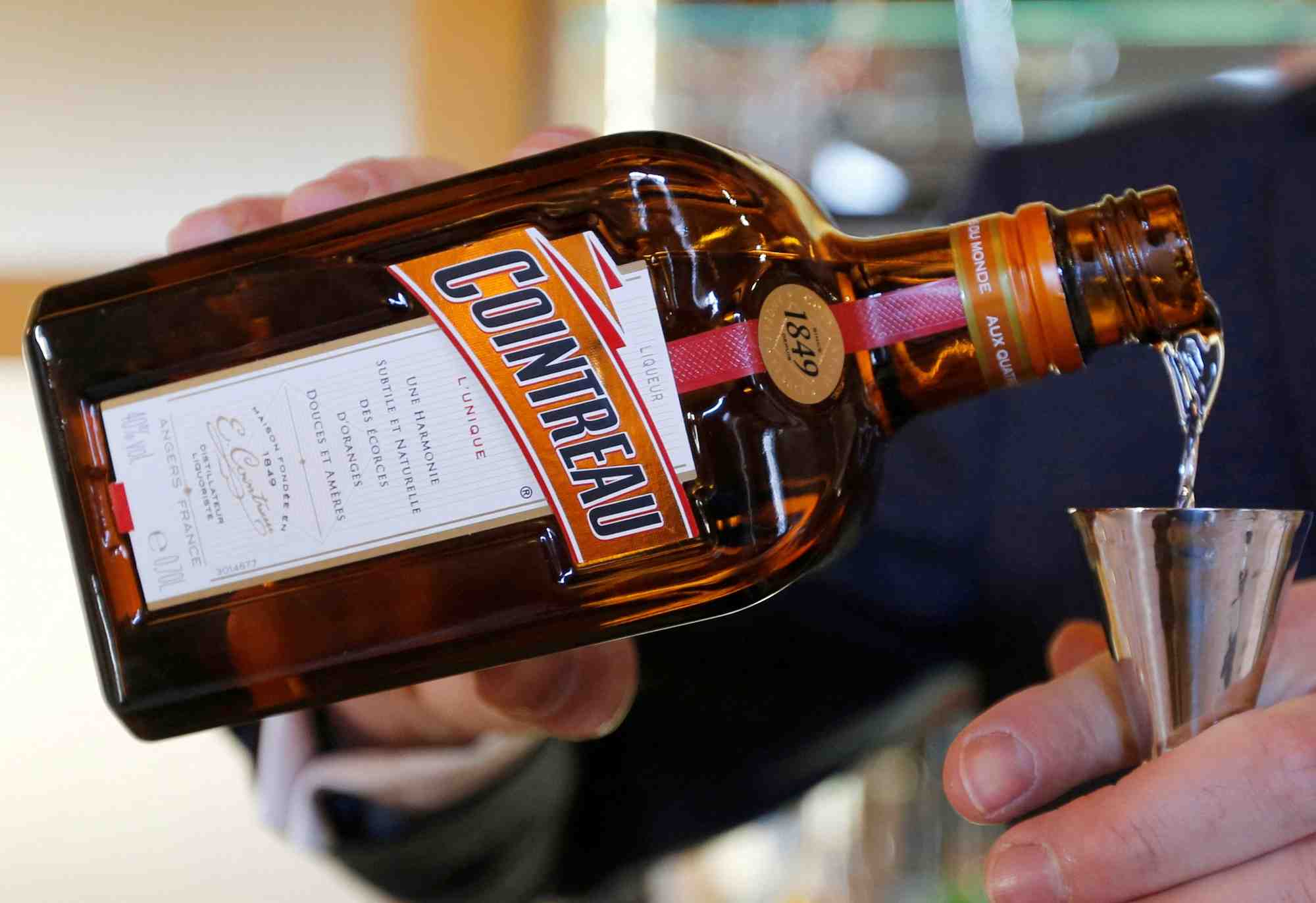 Un homme verse du cointreau dans un verre