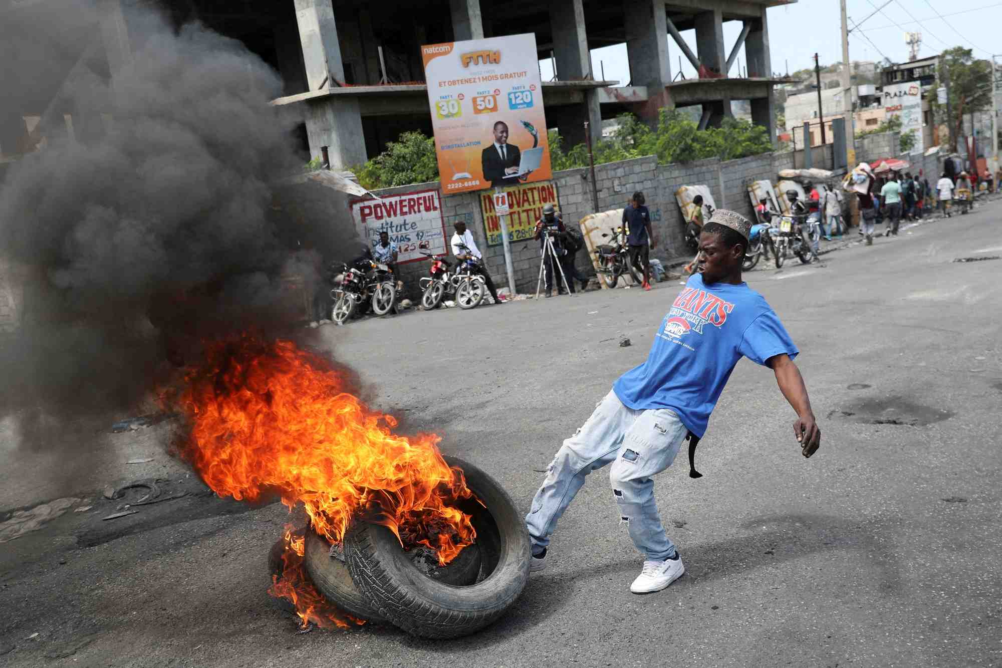 Un homme donne un coup de pied a des pneus en feu lors d'une manifestation antigouvernementale a port-au-prince, en haiti