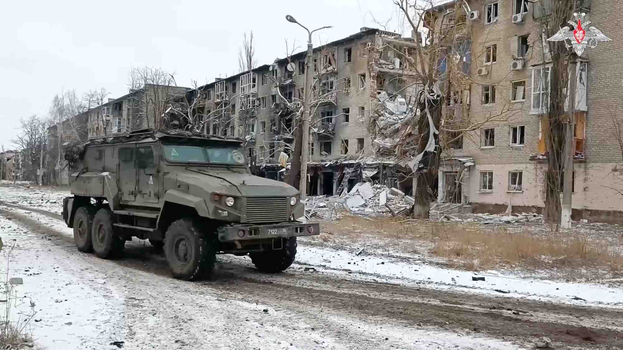 Un vehicule militaire russe passe devant des batiments residentiels endommages dans la ville d'avdiivka