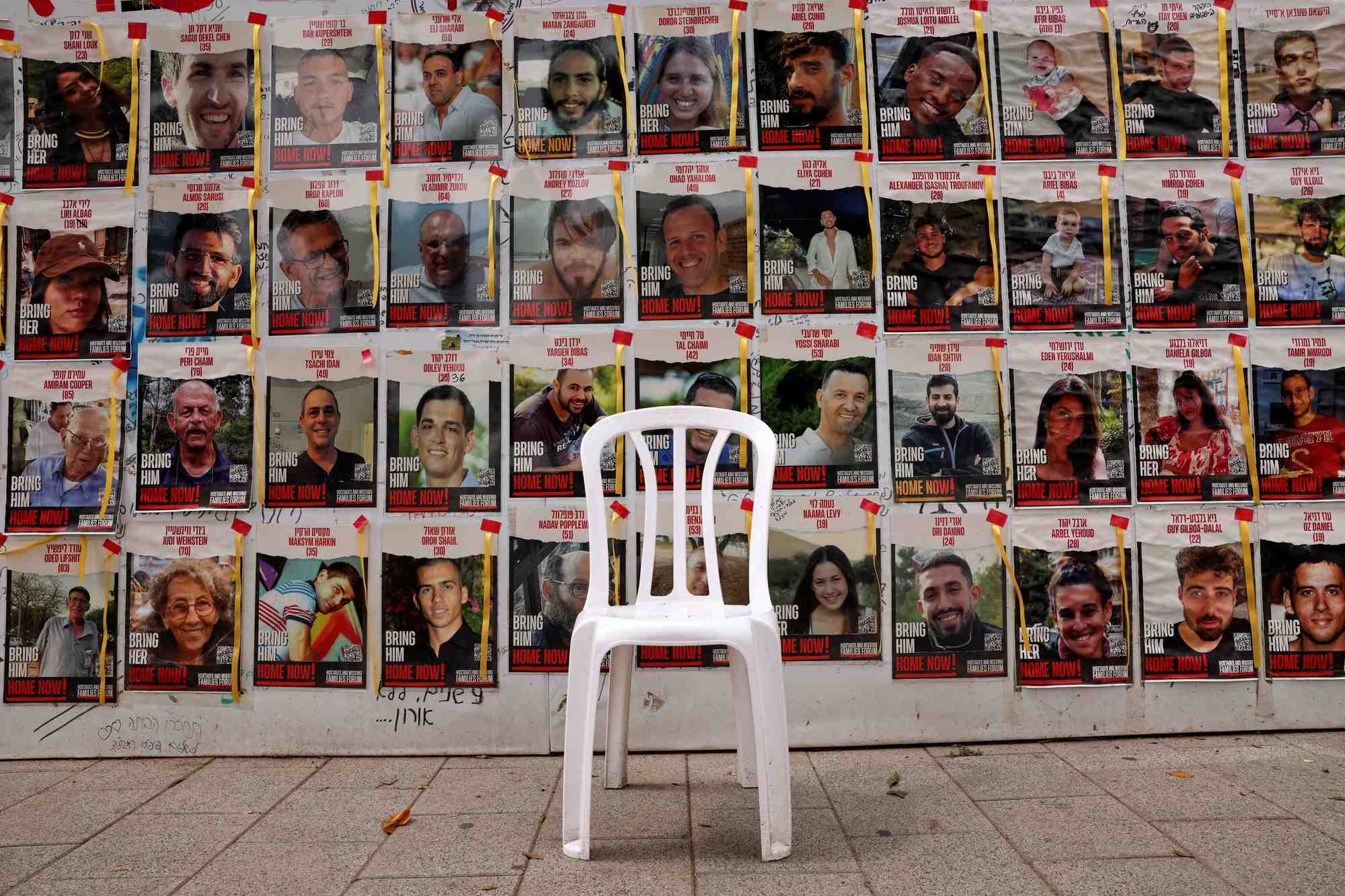Une chaise est laissee devant des affiches avec des photos d'otages