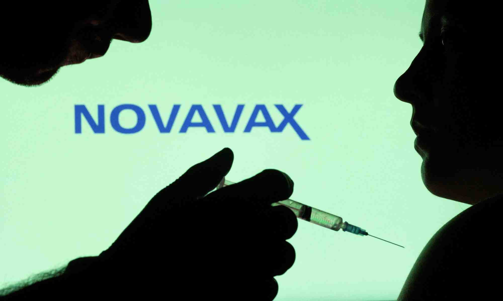 Des personnes posent avec une seringue devant le logo novavax