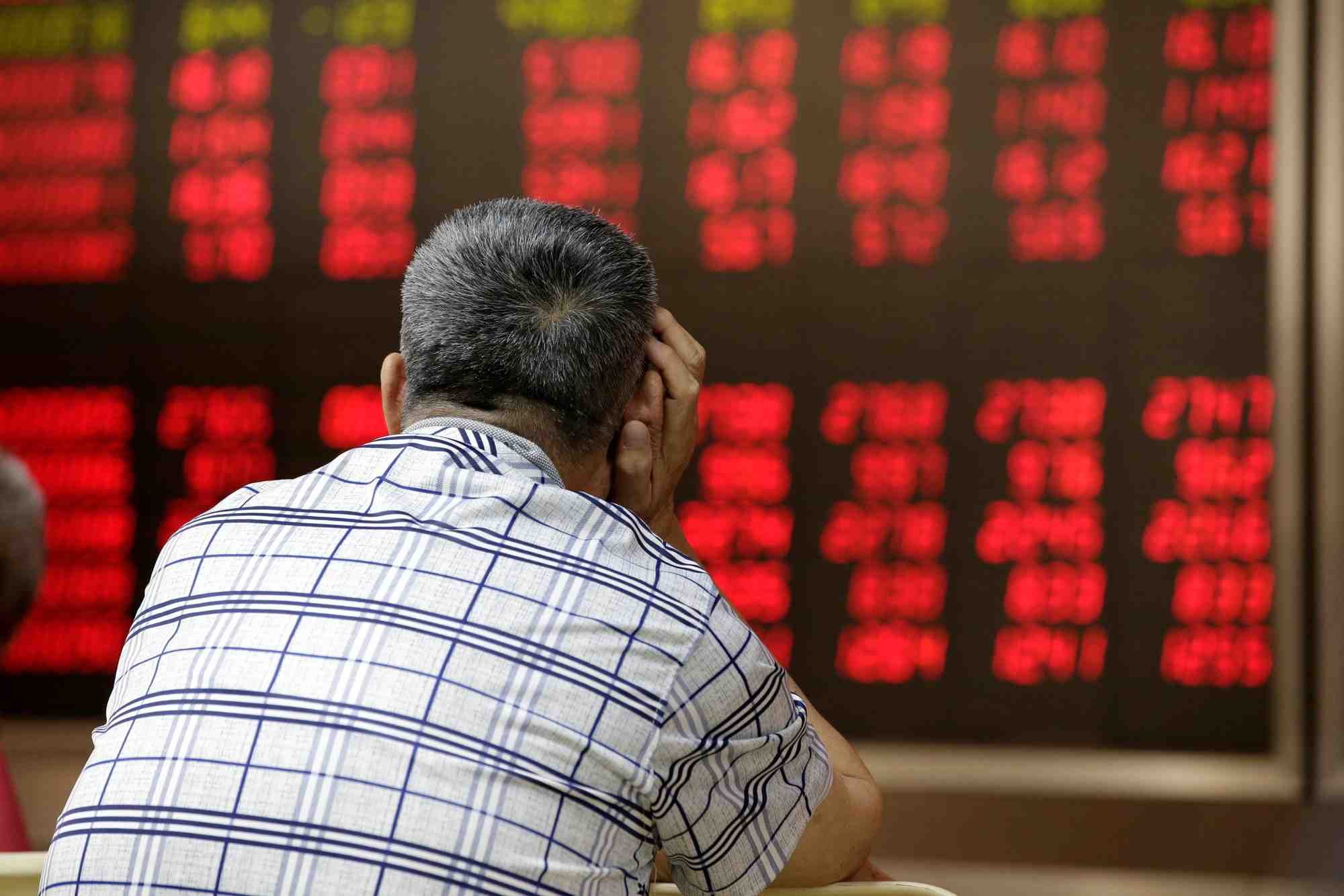 Photo d'un homme regardant un tableau electronique affichant des informations sur les actions a pekin