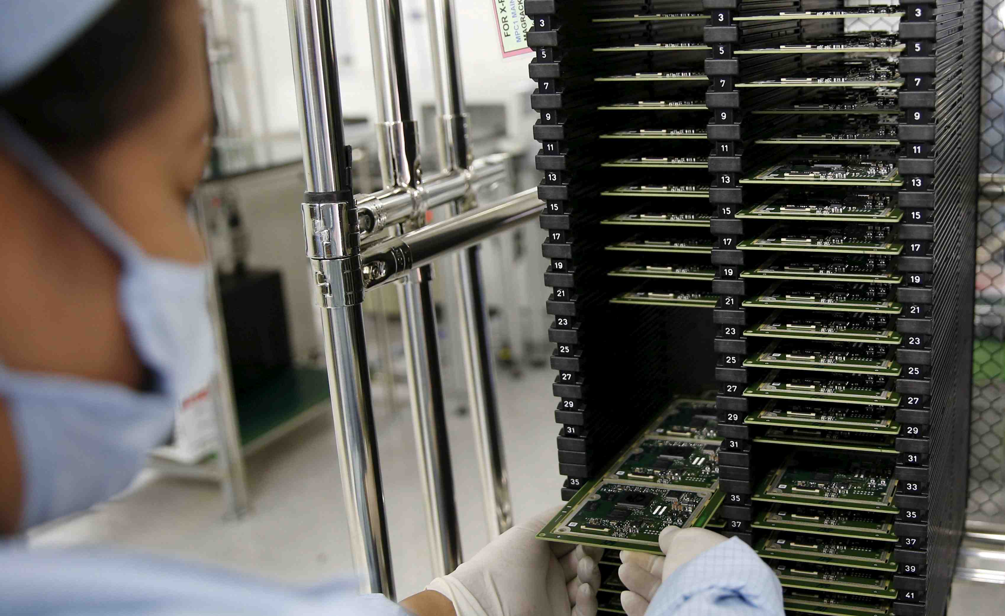 A worker of ayala corp's integrated micro-electronics inc. (imi) removes computer chips from a shelve at an electronics assembly line in binan, laguna