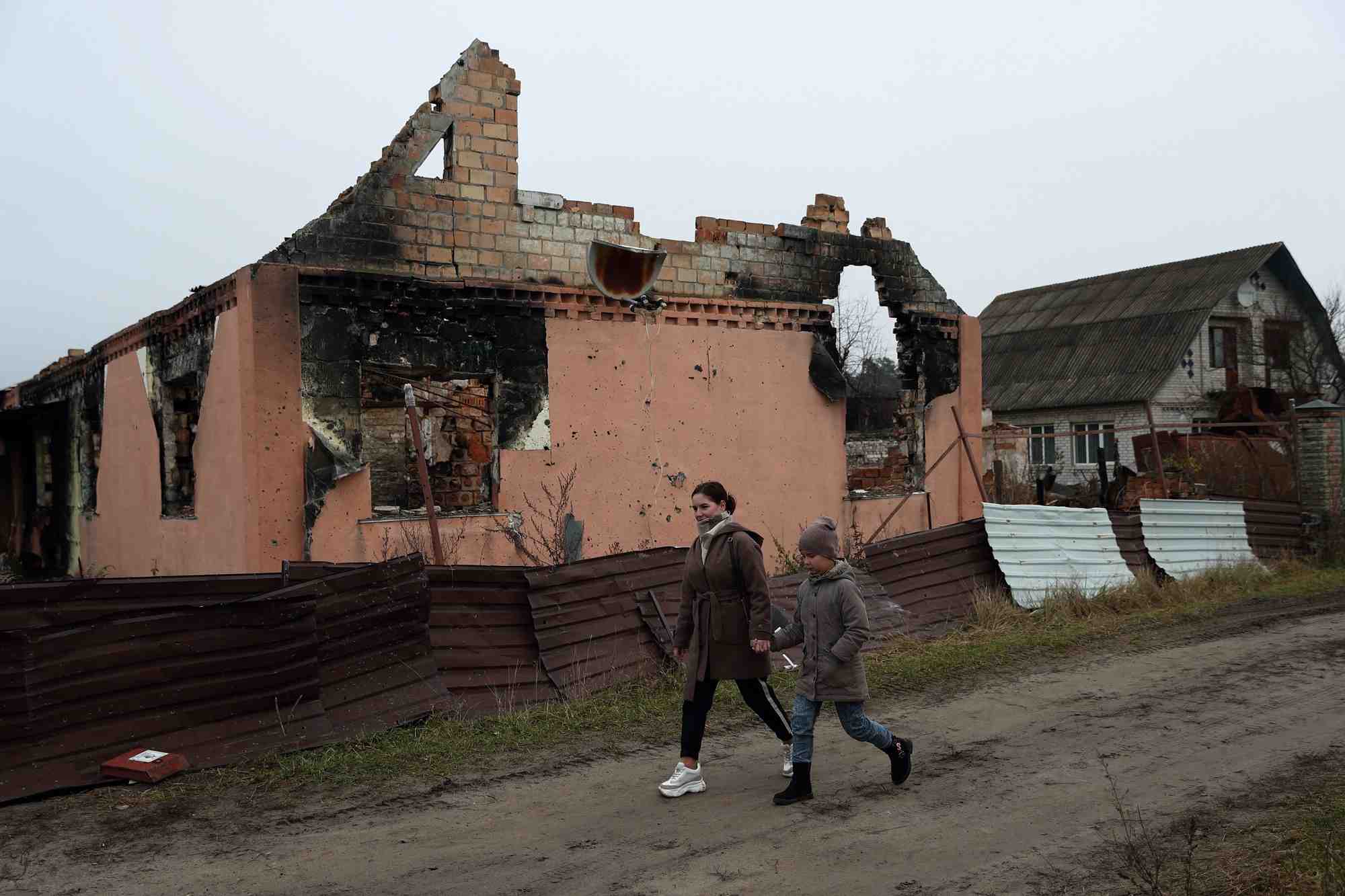 Kateryna tyshchenko et sa demi-soeur de 9 ans, yuliia zaika, passent devant une maison detruite dans le village de moshchun