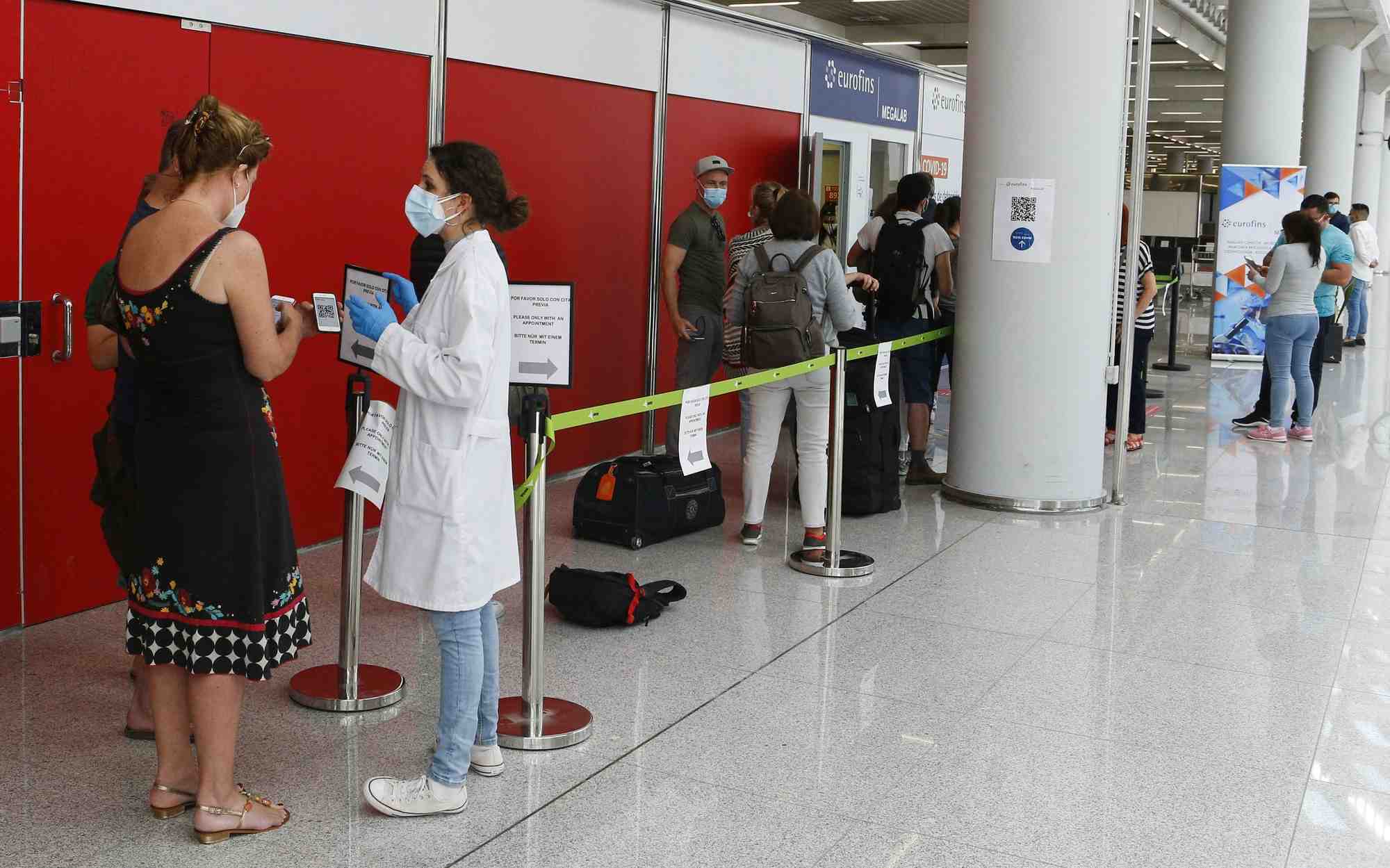 Des passagers font la queue devant un point de depistage du coronavirus a l'aeroport de son sant joan a palma de majorque