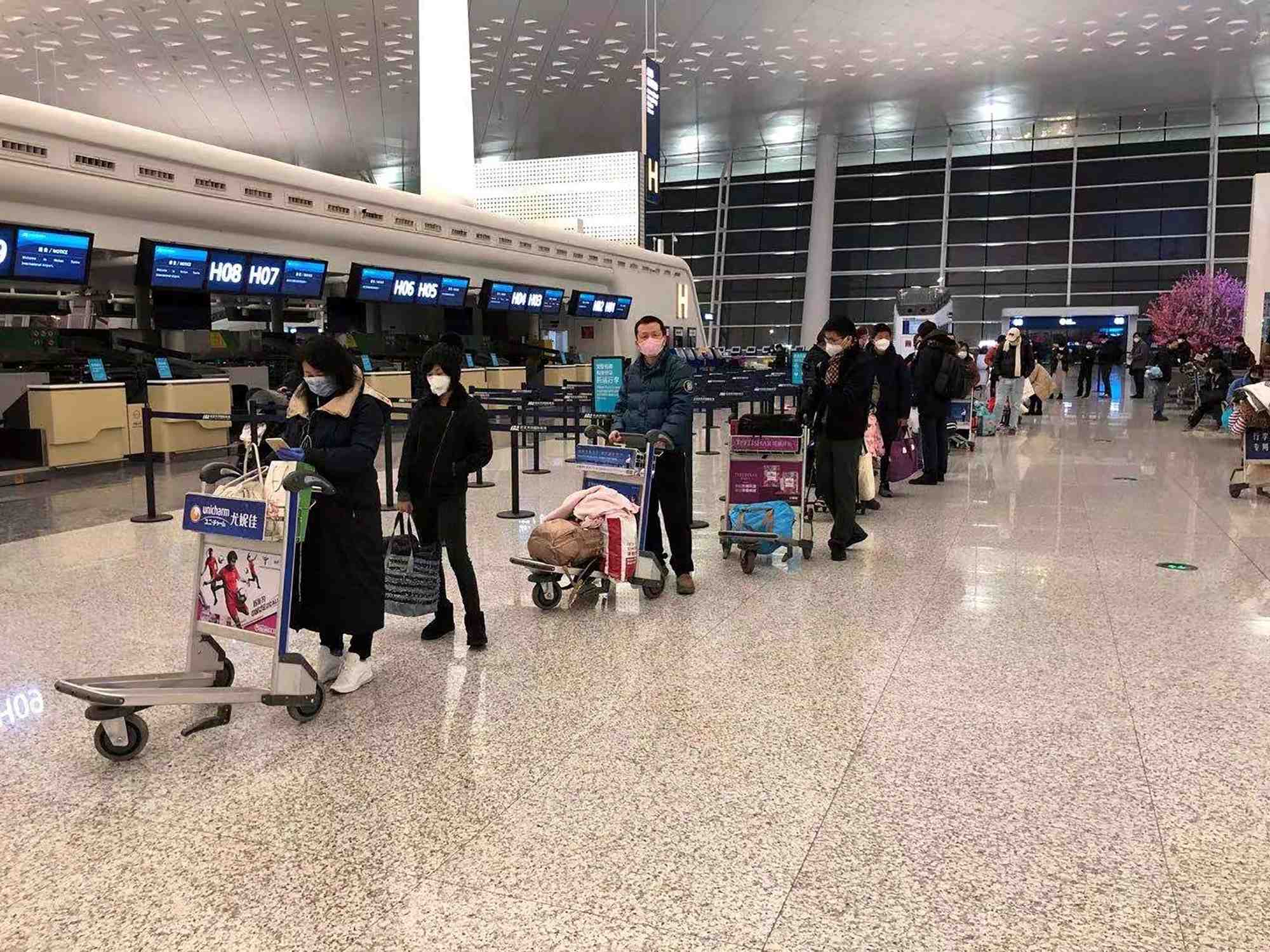 Le le 7 février 2020, à l'aéroport international de Wuhan Tianhe (Chine), des passagers font la queue pour monter à bord d'un avion-cargo affrété par le Département d'État américain pour évacuer de Chine les ressortissants américains et canadiens à cause du nouveau coronavirus.