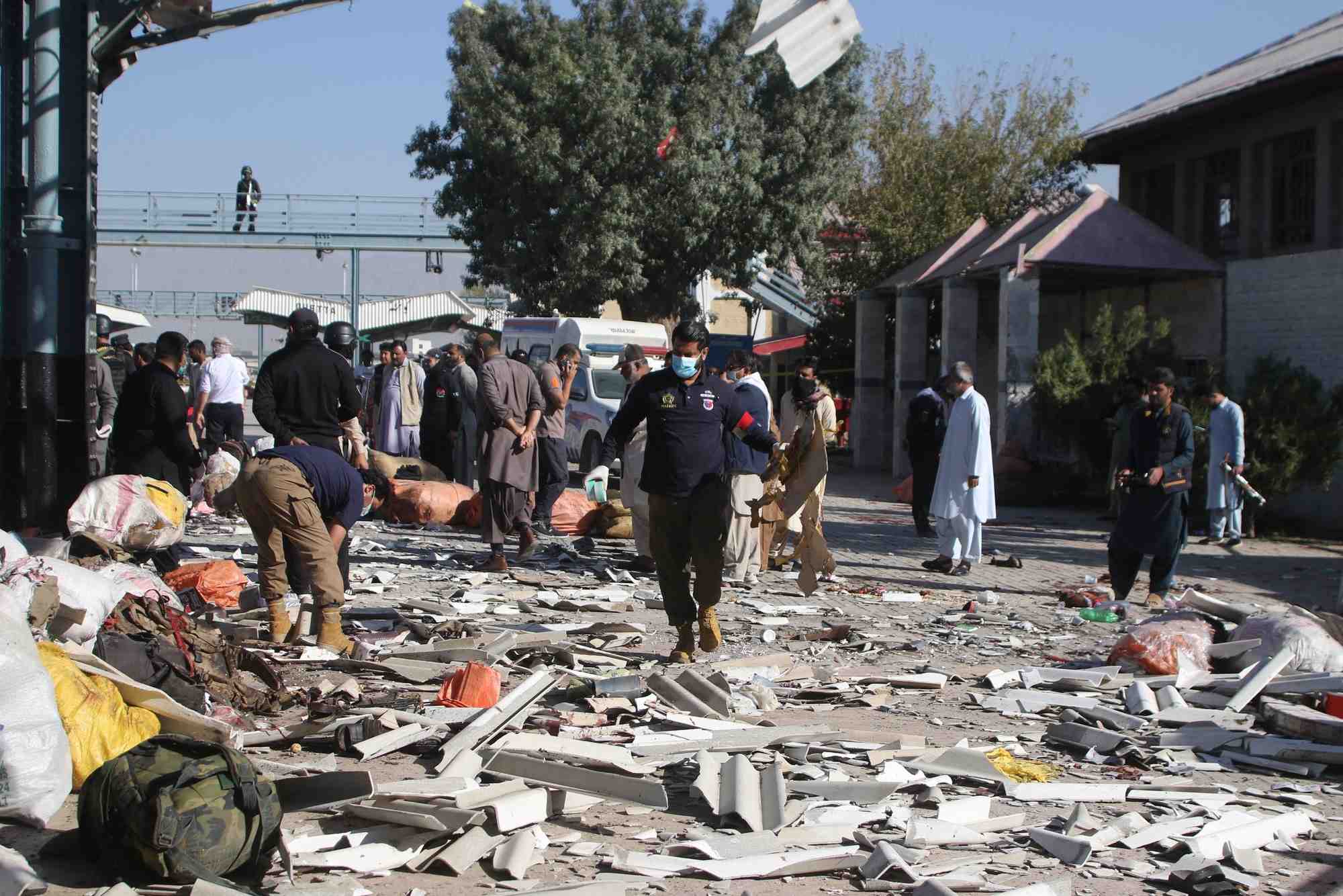 Un officier de police examine le site au milieu des debris apres l'explosion d'une bombe dans une gare ferroviaire a quetta.