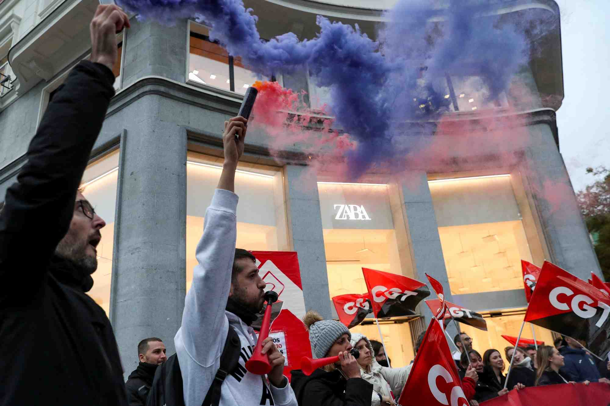 Des personnes tiennent des drapeaux du syndicat espagnol cgt lors d'une manifestation devant un magasin de vetements zara a madrid