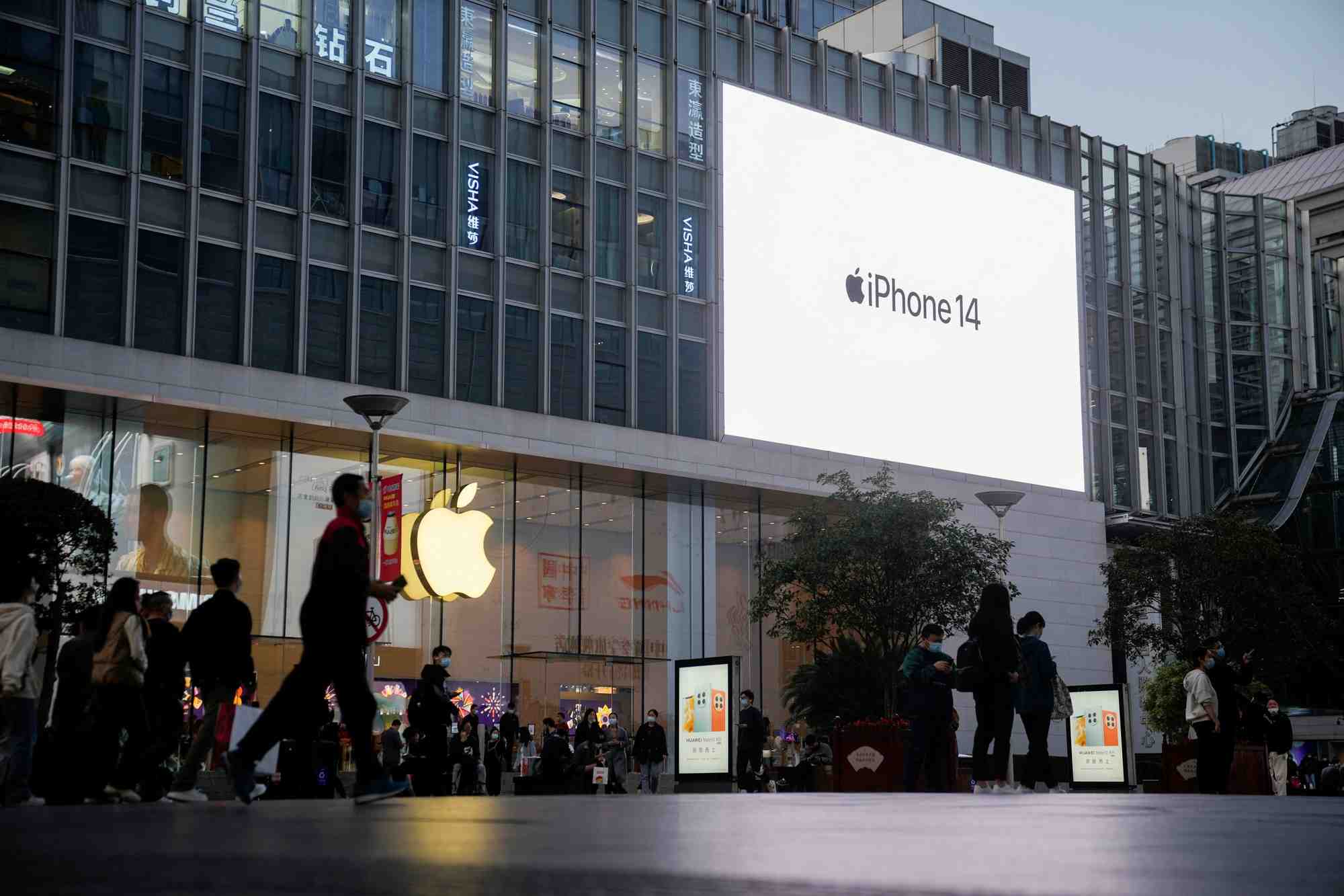 People walk near a display advertising the apple iphone 14 outside its store in shanghai