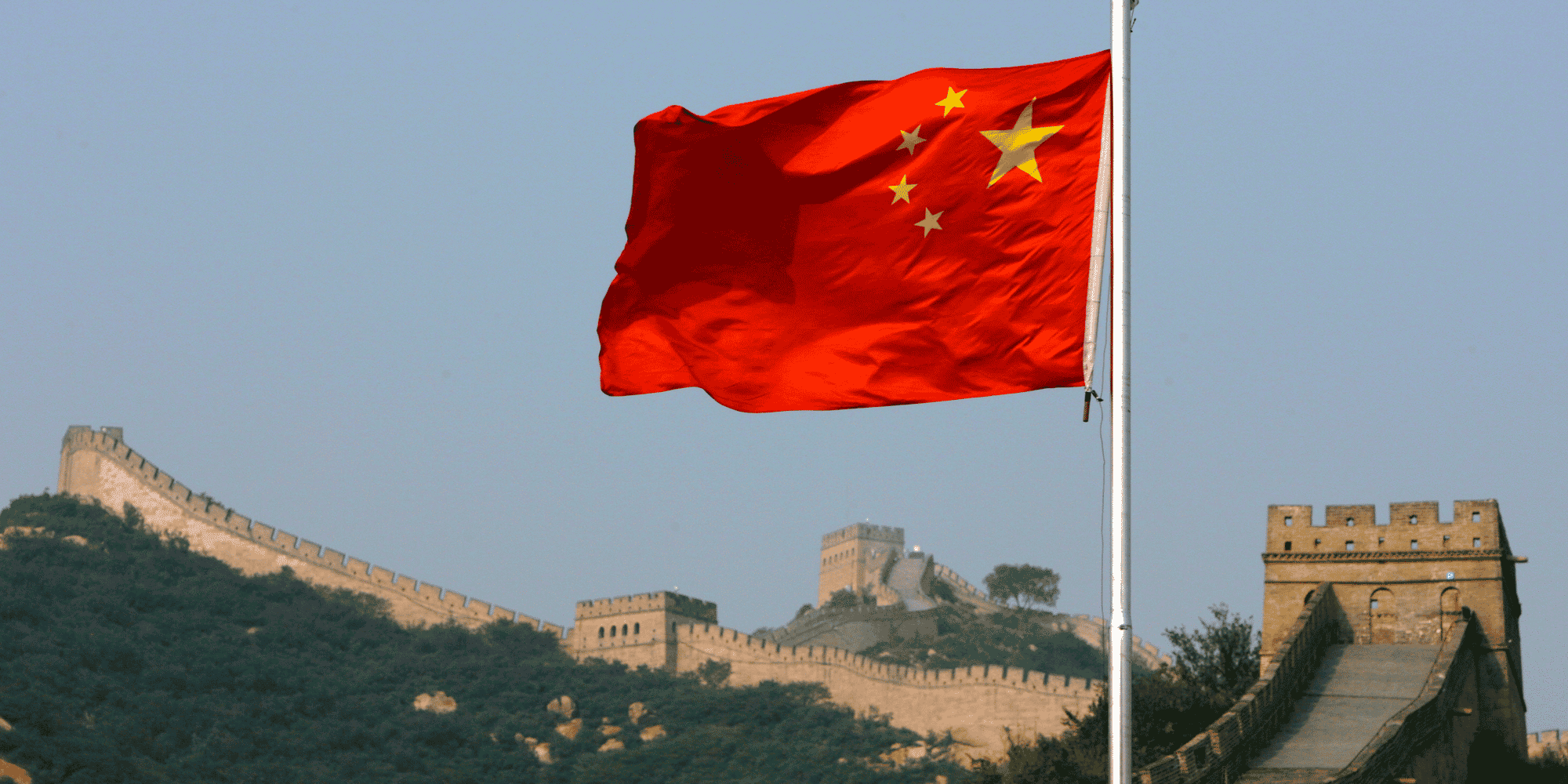 Un drapeau chinois flotte devant la grande muraille de chine, situee au nord de pekin