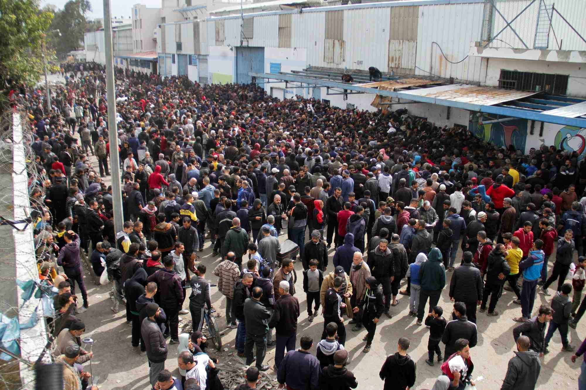 Des palestiniens se rassemblent pour recevoir de l'aide devant un entrepot de l'unrwa dans la ville de gaza