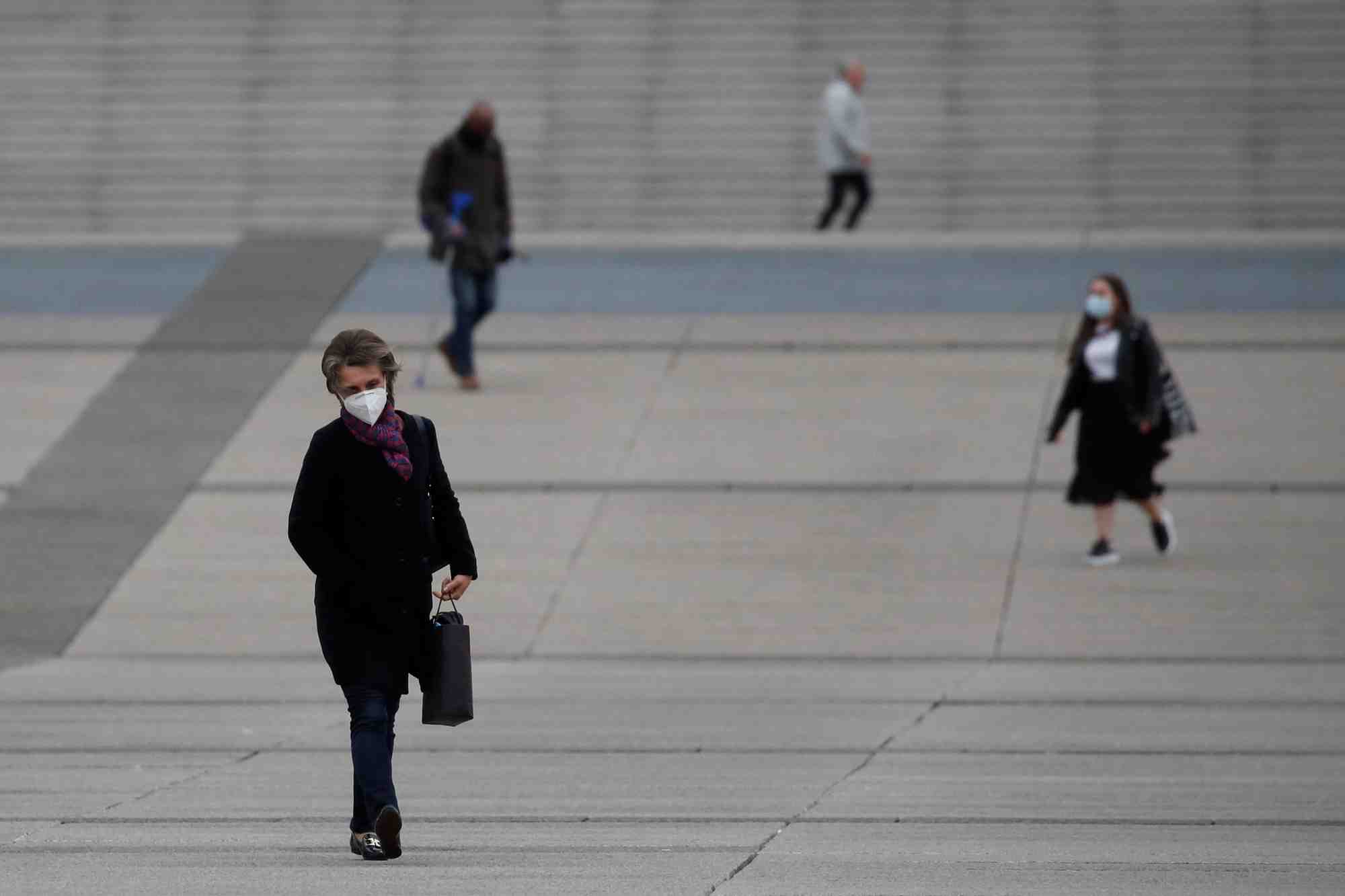 Coronavirus : une femme portant un masque marche dans le quartier La Défense à Paris