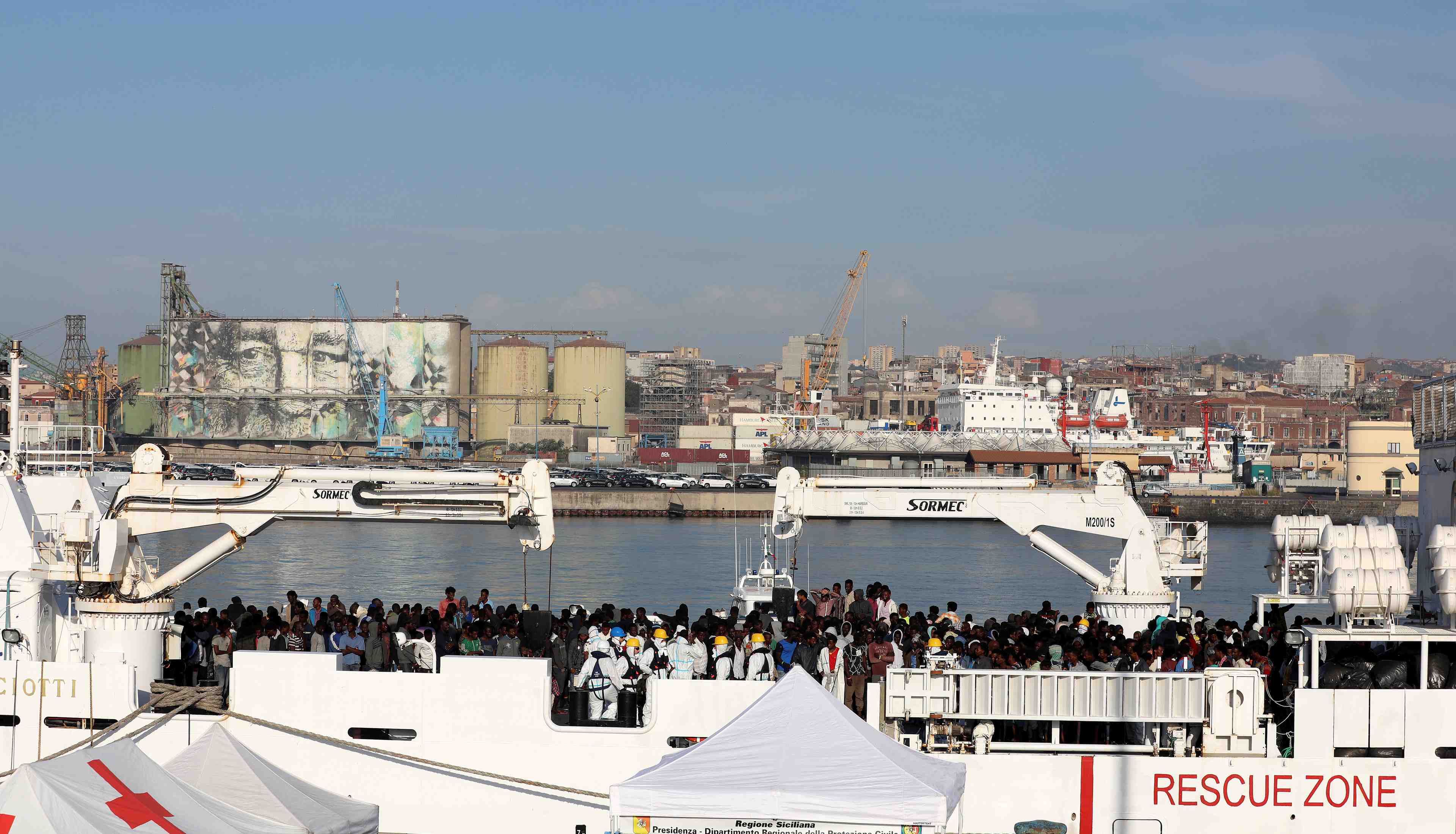 Migrants wait to disembark italian coast guard's vessel "diciotti" as they arrive at the catania harbour