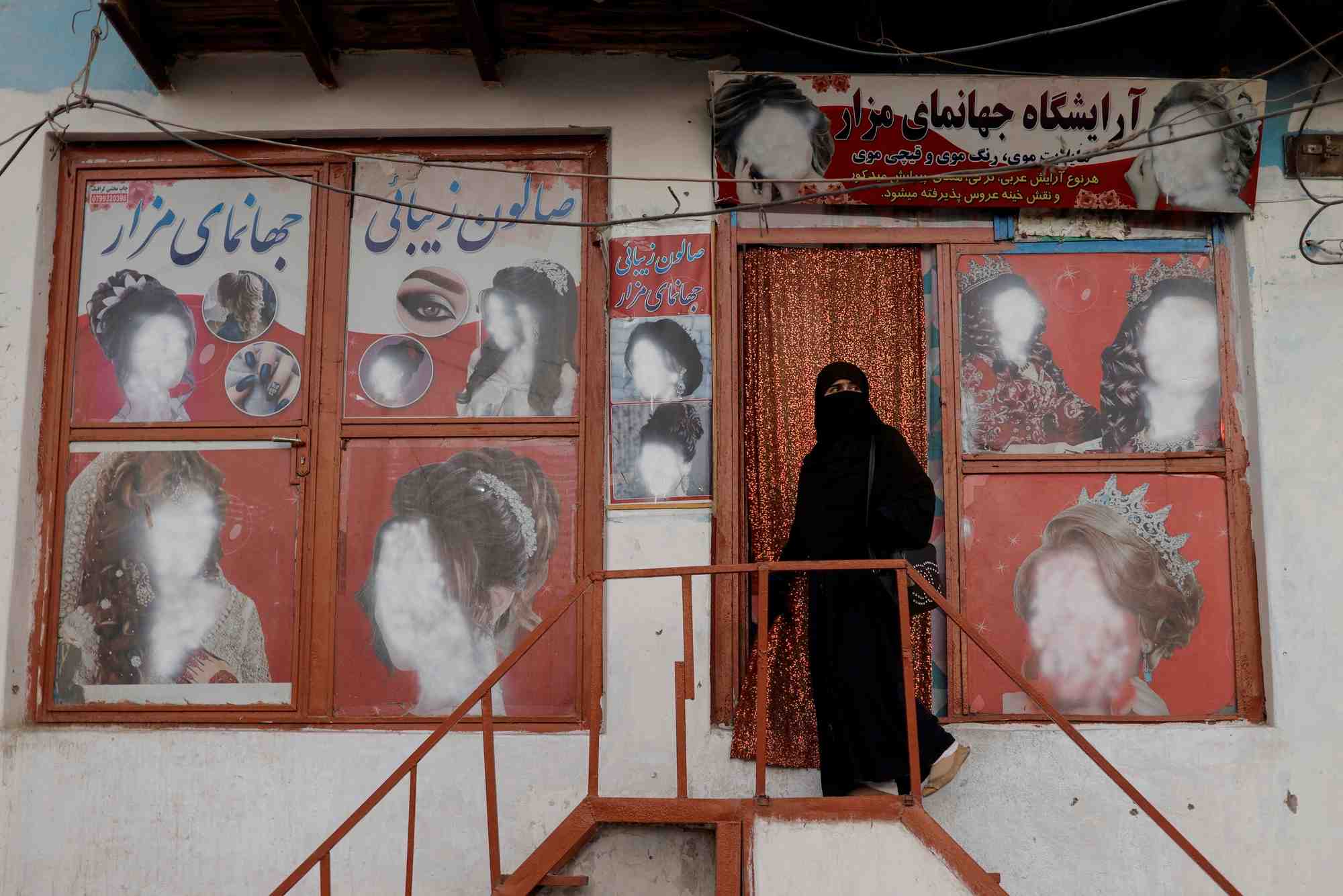 Une femme entrant dans un salon de beaute a kaboul, en afghanistan
