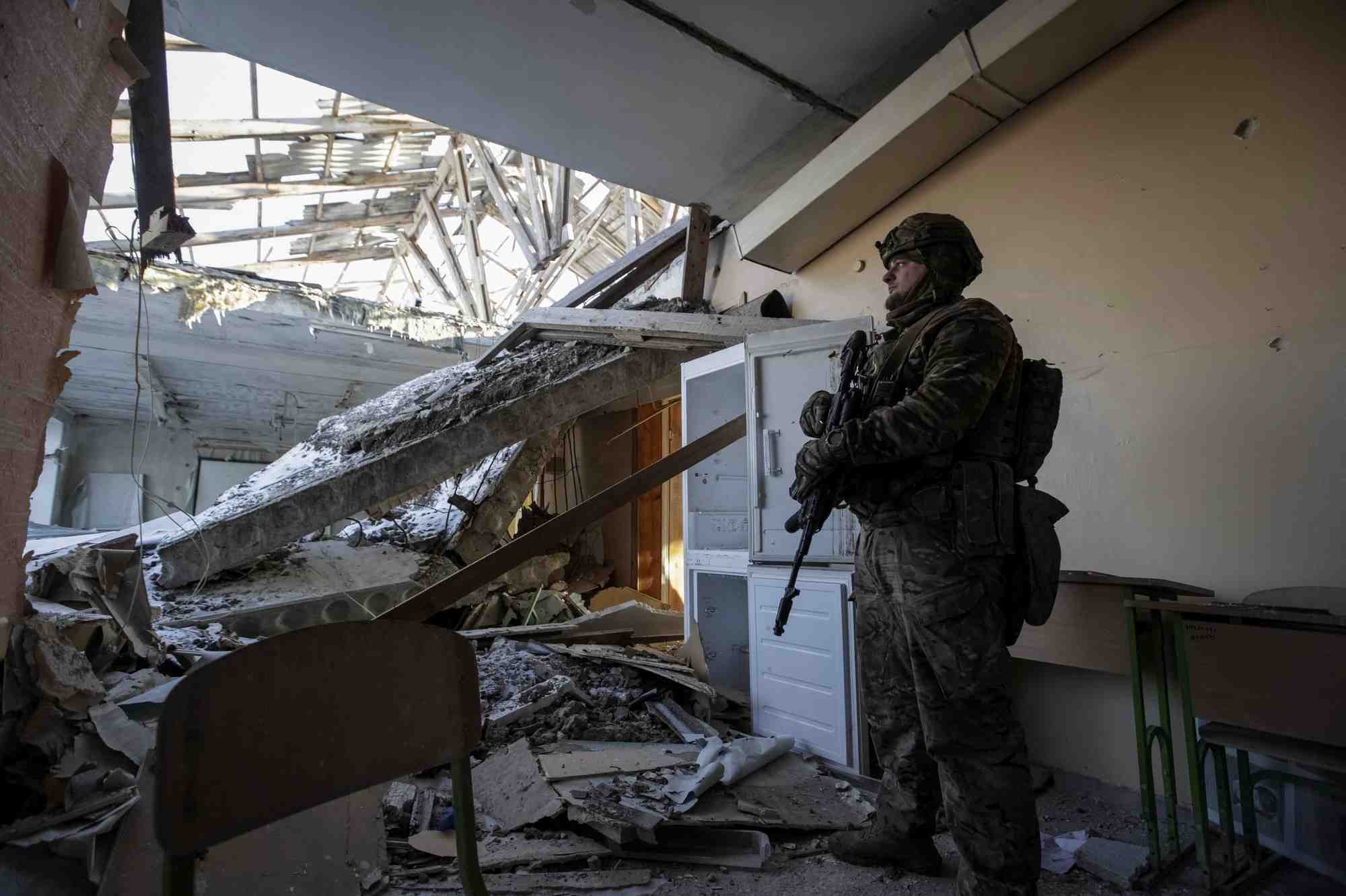 Un militaire ukrainien dans une ecole detruite