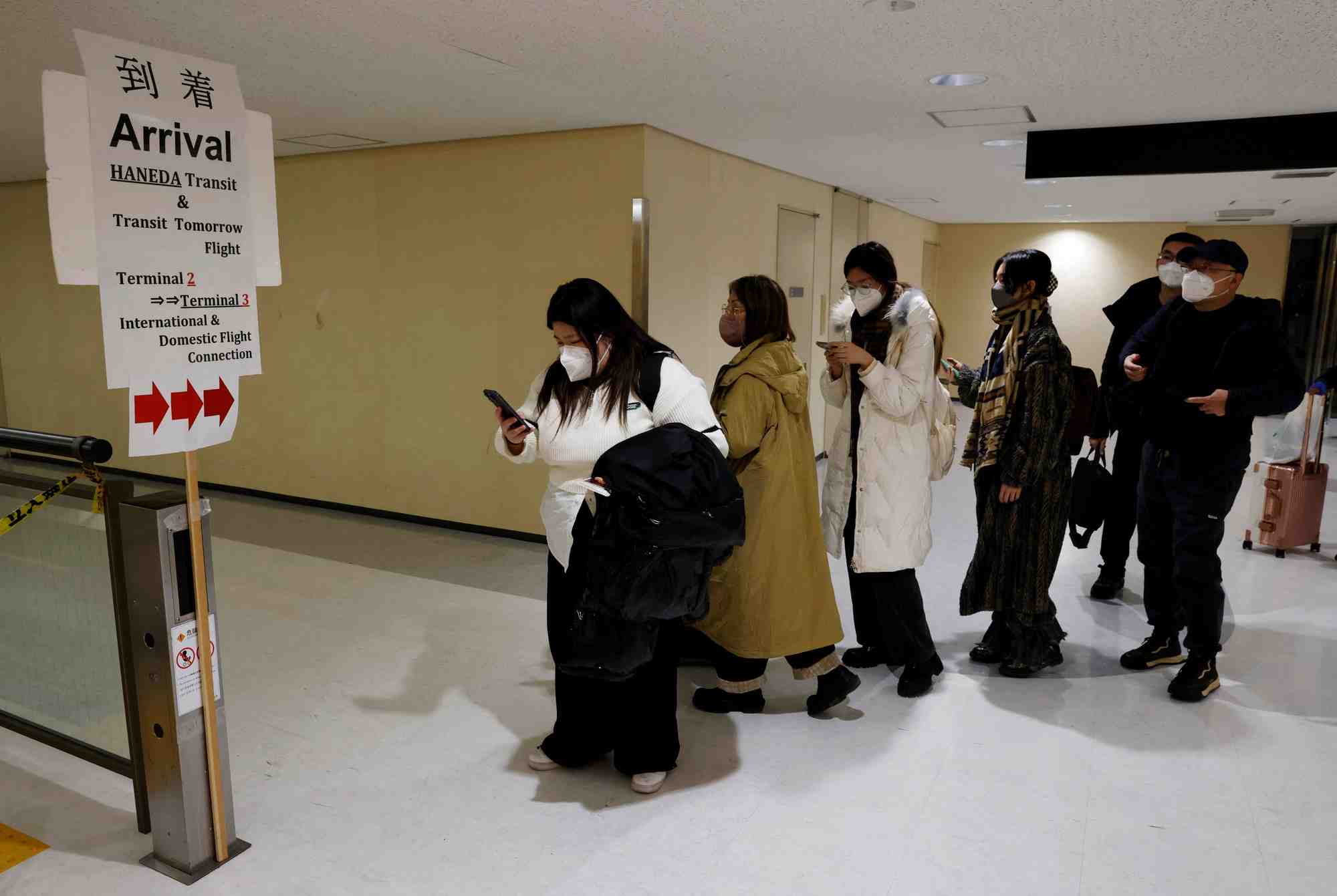Des passagers d'un avion en provenance de pekin se dirigeant vers la zone de test du coronavirus