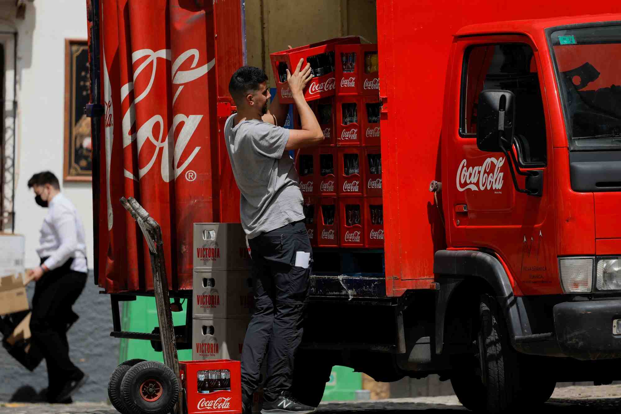 Un livreur decharge des caisses de bouteilles coca-cola d'un camion a ronda, en espagne
