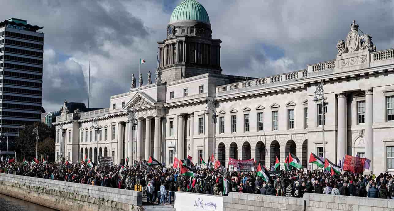 Un grand nombre de manifestants munis de banderoles, de drapeaux et de pancartes défilent dans les rues de Dublin en direction de l'ambassade d'Israël pendant une manifestation, fin 2024.
