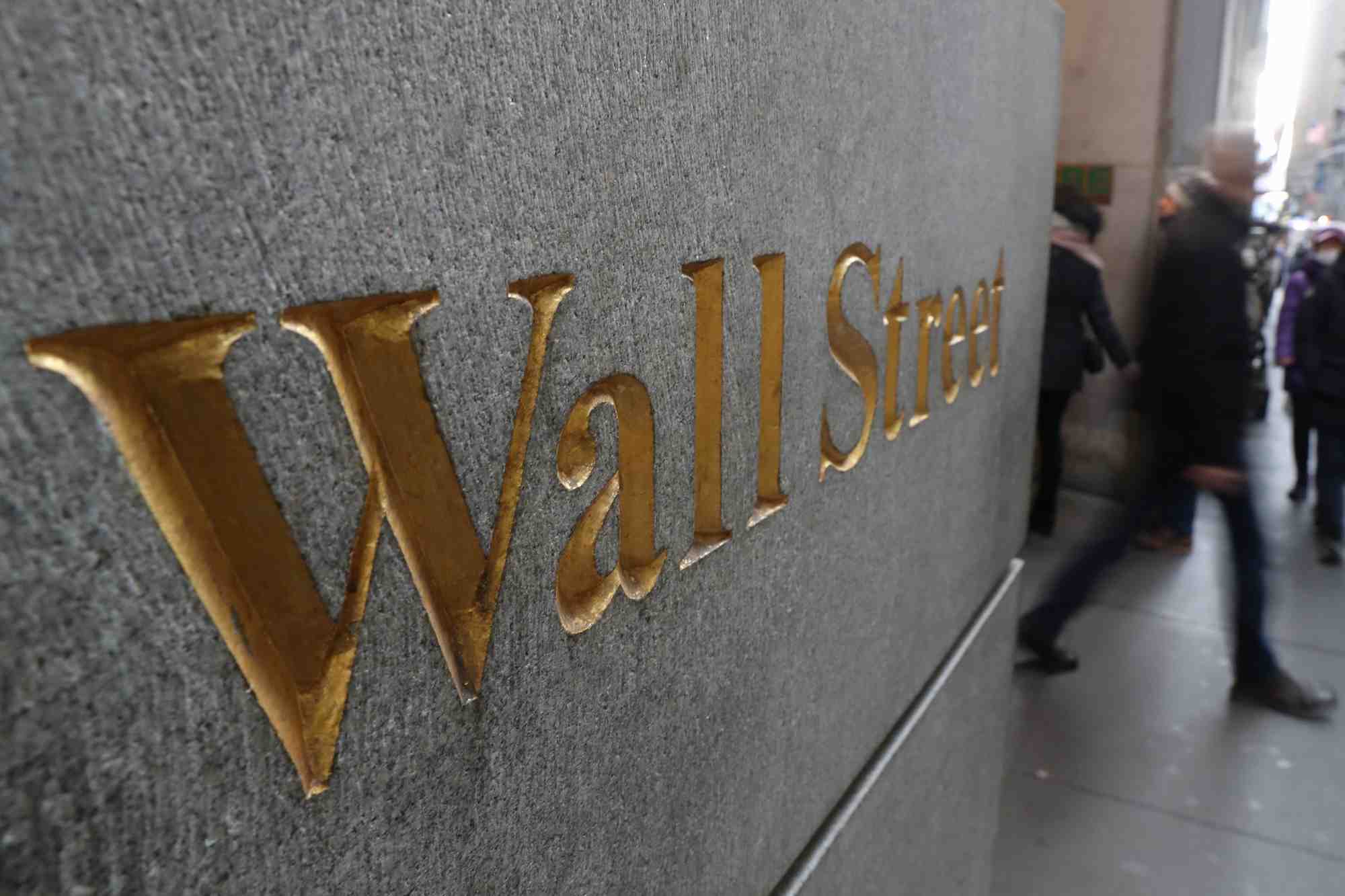 Un panneau de rue indiquant Wall Street est visible à l'extérieur de la Bourse de New York