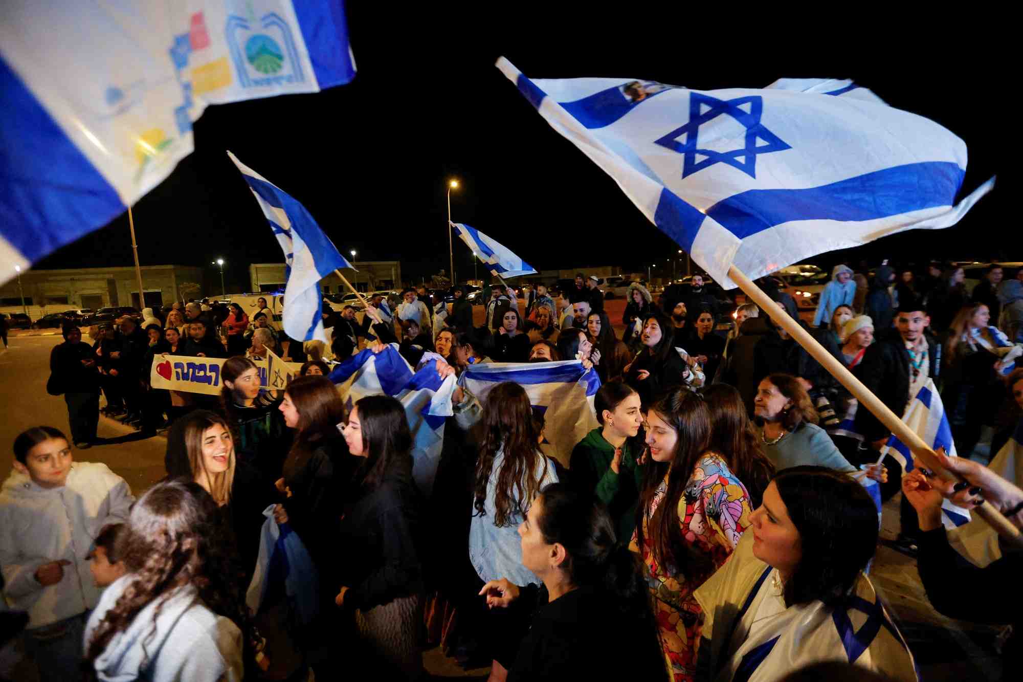 Des personnes brandissent des drapeaux israeliens a ofakim, en israel, apres la liberation des otages captures lors de l'attaque du 7 octobre par le hamas