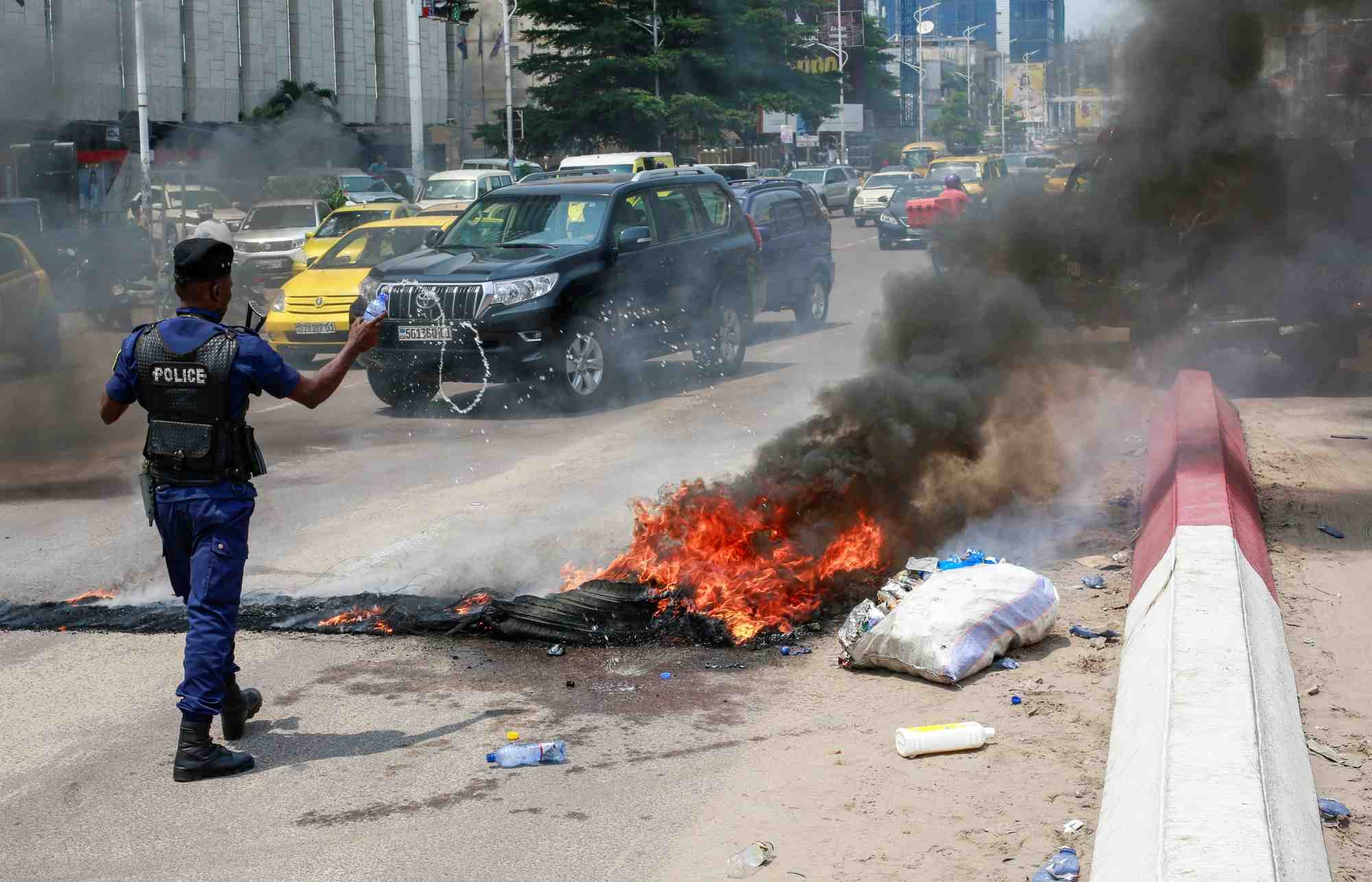 Un policier jette de l'eau sur des pneus en feu apres une manifestation pres de l'ambassade americaine a kinshasa, en rdc