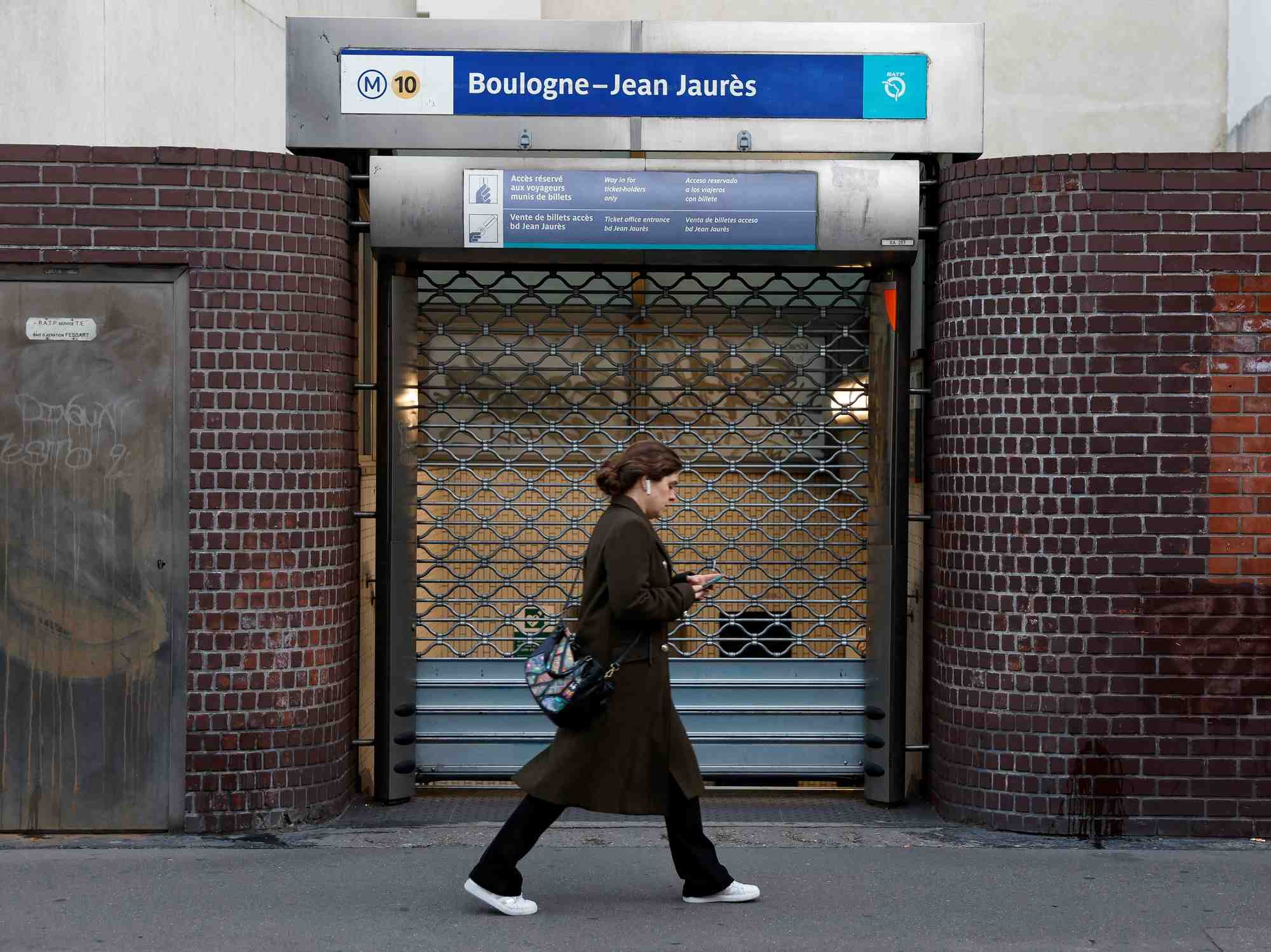 Une femme passe devant la station de metro boulogne-billancourt pendant la journee de greve a la ratp