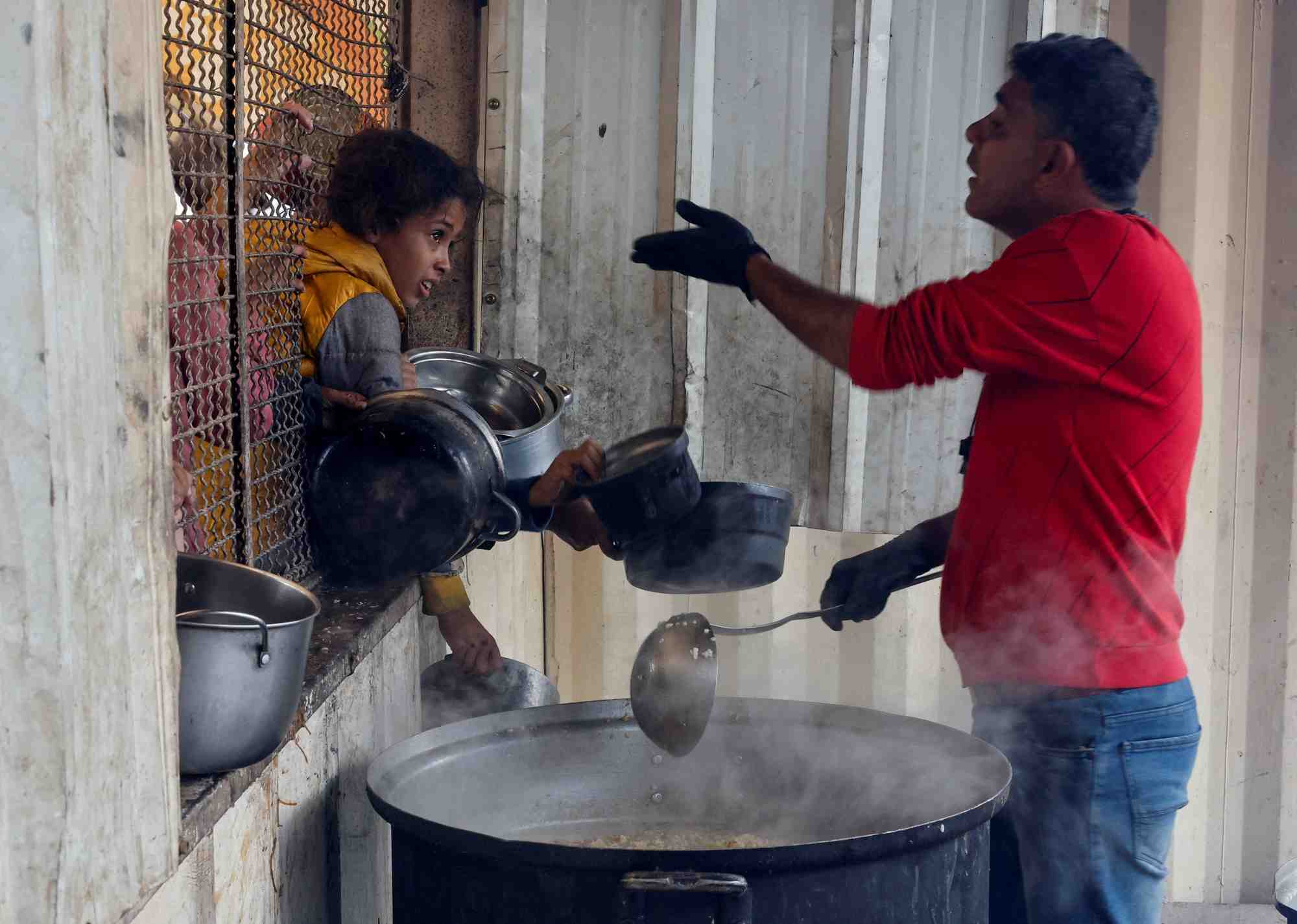 Des palestiniens se rassemblent pour recevoir de la nourriture preparee par une cuisine caritative, a khan younis