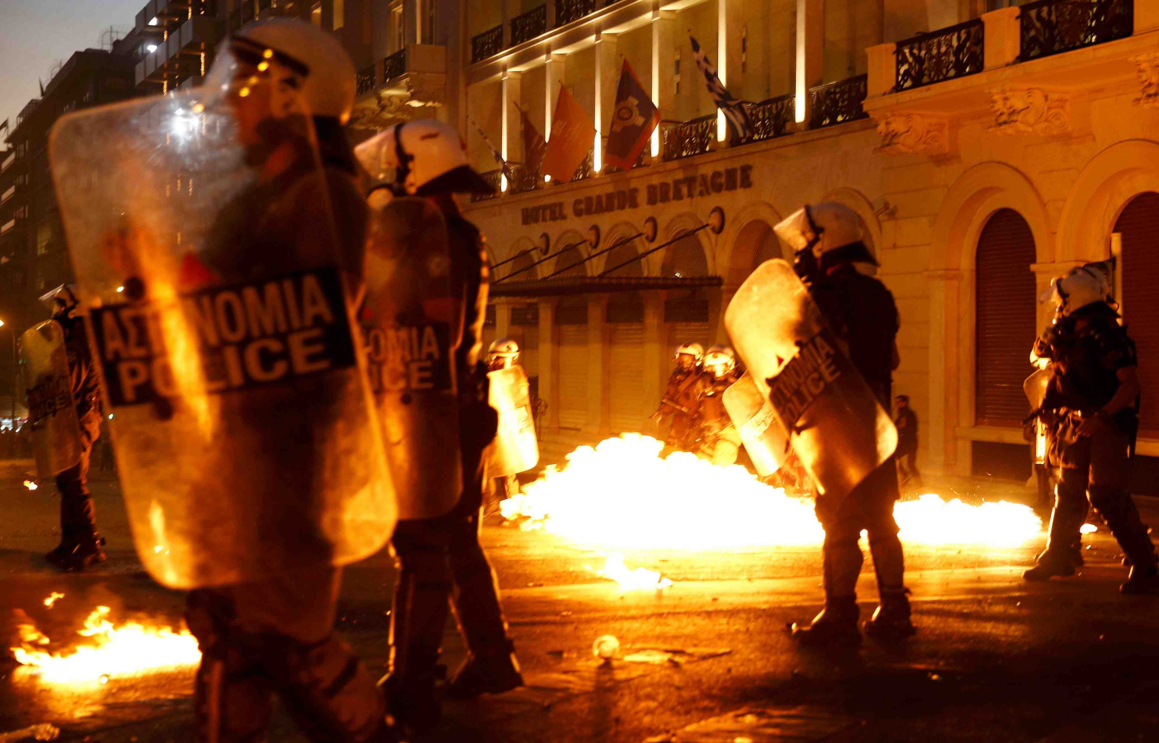 Riot police stand amongst flames from petrol bombs thrown by a small group of anti-austerity demonstrators in athen