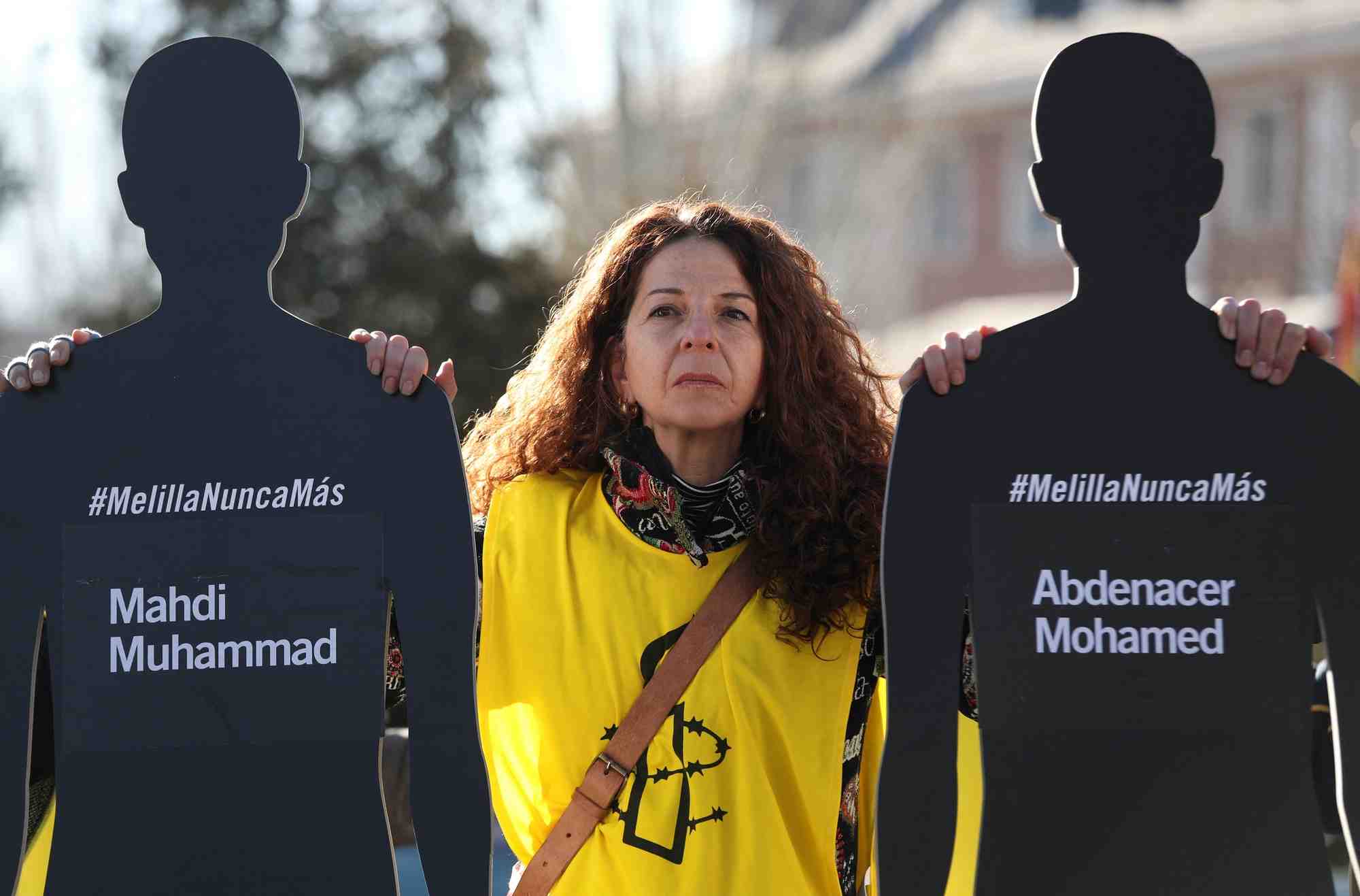 Une femme portant le logo d'amnesty international place des silhouettes et des noms de migrants devant le palais de la moncloa en espagne pour protester contre l'incident de melilla