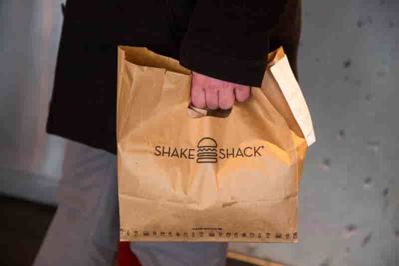 A customer holds a bag full of food inside of a shake shack store in new york