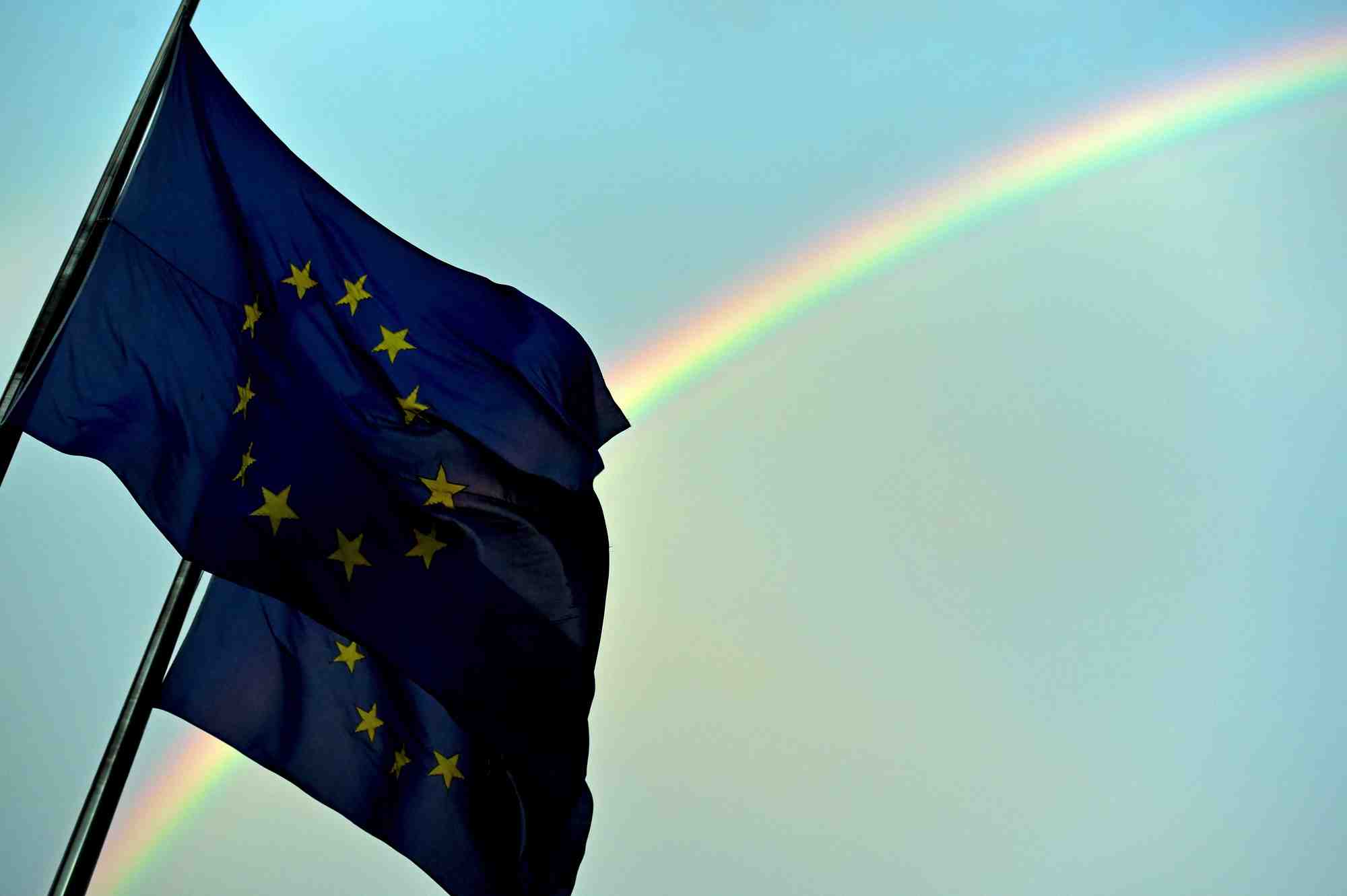 Un arc-en-ciel est visible derriere les drapeaux europeens