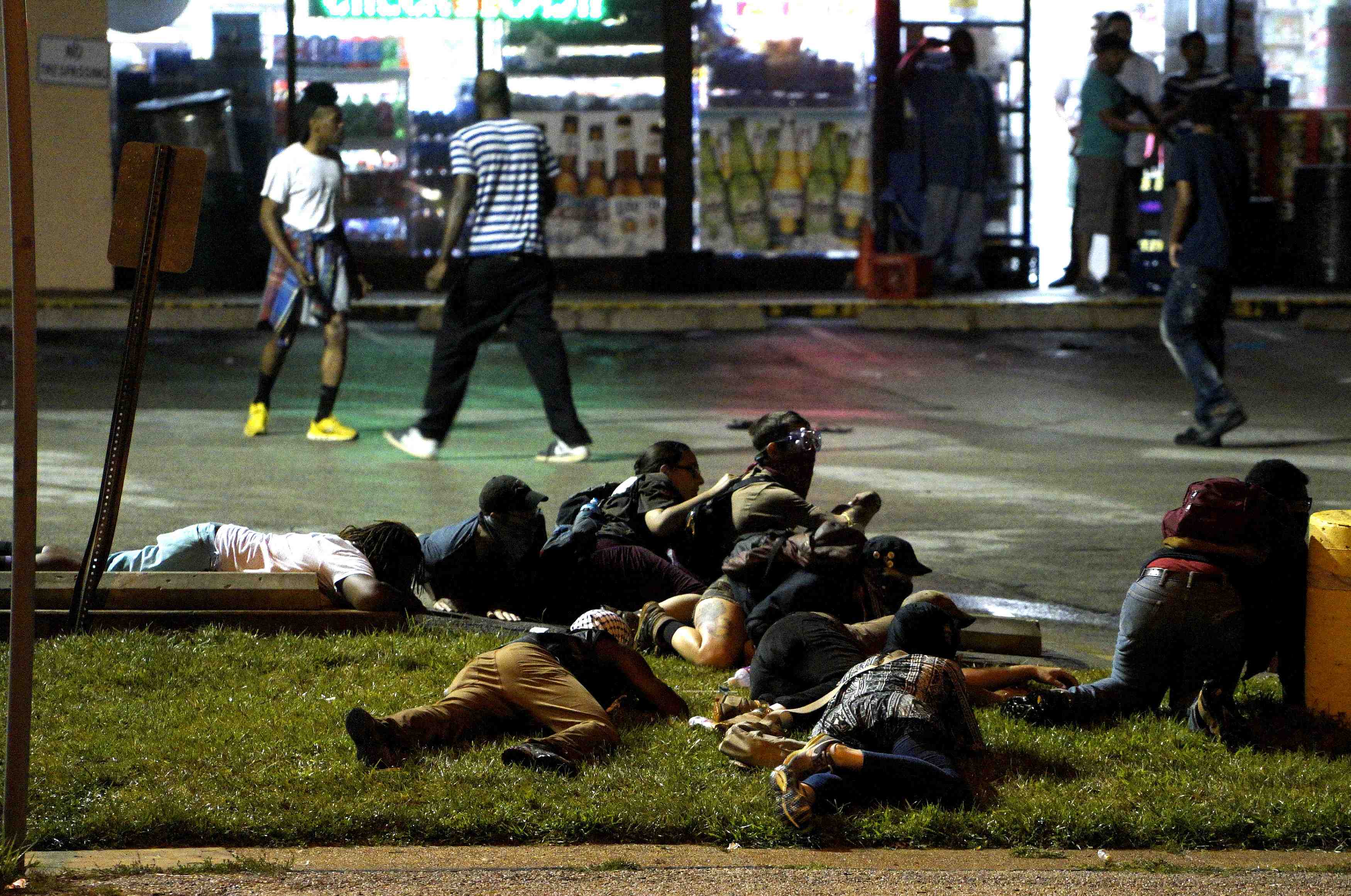 Protesters fall to the ground to take cover after shots were fired in a police-officer involved shooting in ferguson