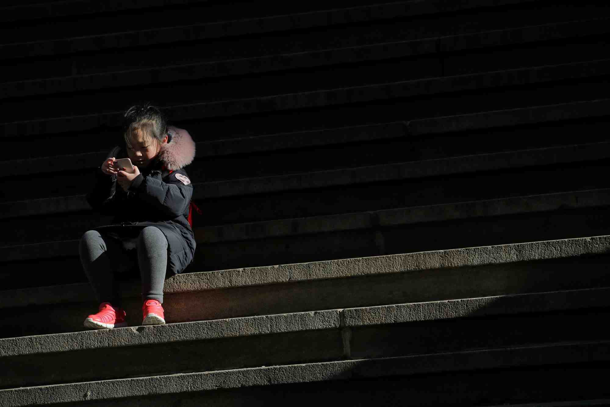 A child uses a smartphone on wall st. during the morning commute in new york