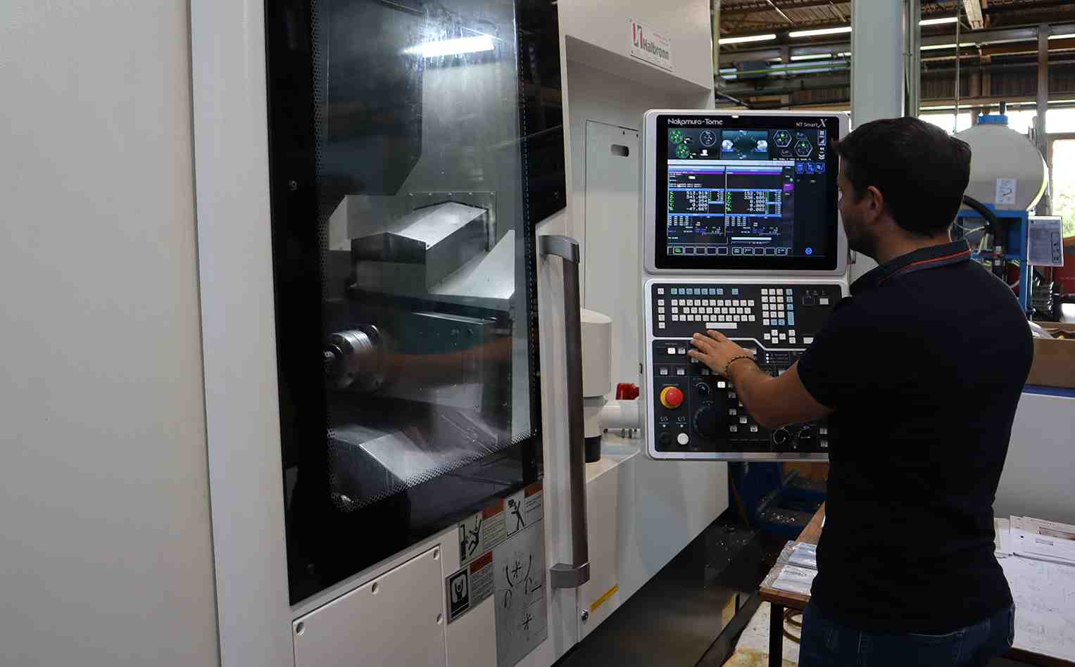 Un opérateur de Suntec Industries France manipule la machine Nakamura NTJ100 : Tour bi-broches & 10 axes pour l’usinage de moyeu et corps aluminium.