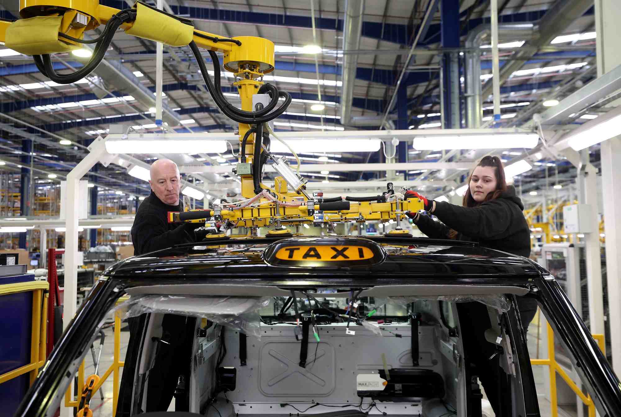 Des ouvriers montent un panneau de toit sur la ligne de production du taxi electrique tx a l'interieur de l'usine levc (london electric vehicle company) a coventry.
