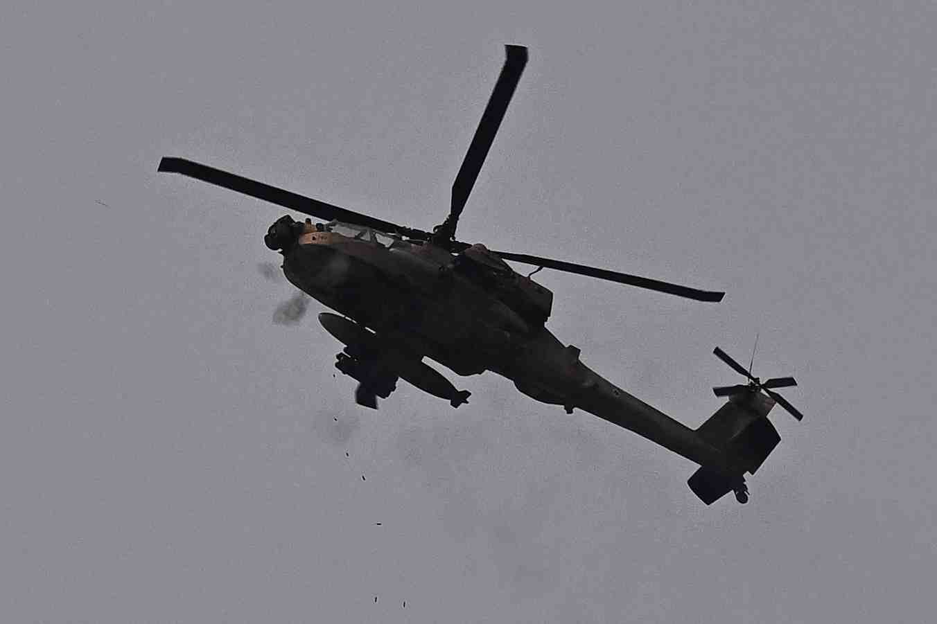 Un helicoptere d'attaque ah-64 apache de l'armee de l'air israelienne tire avec sa mitrailleuse, pres de la frontiere entre l'israel et la bande de gaza