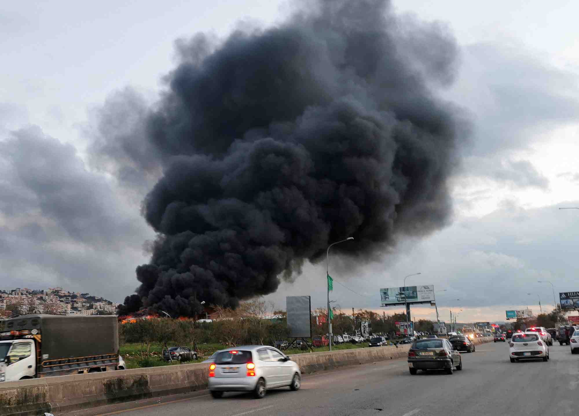Des vehicules roulent alors que de la fumee s'eleve d'un site touche par une frappe aerienne pres de la ville de ghaziyeh, au liban