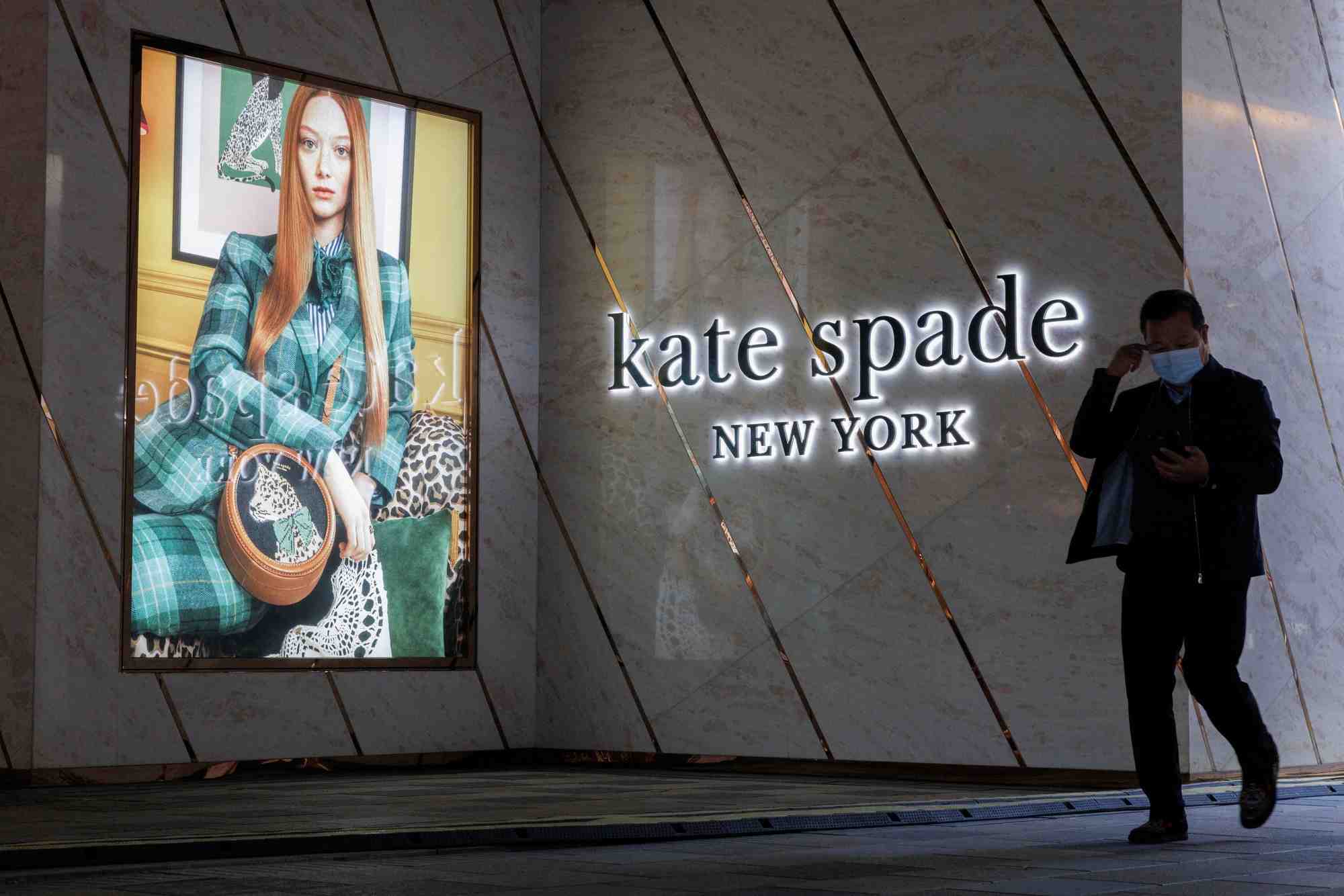 Un homme passe devant un magasin kate spade dans un quartier commercant de pekin