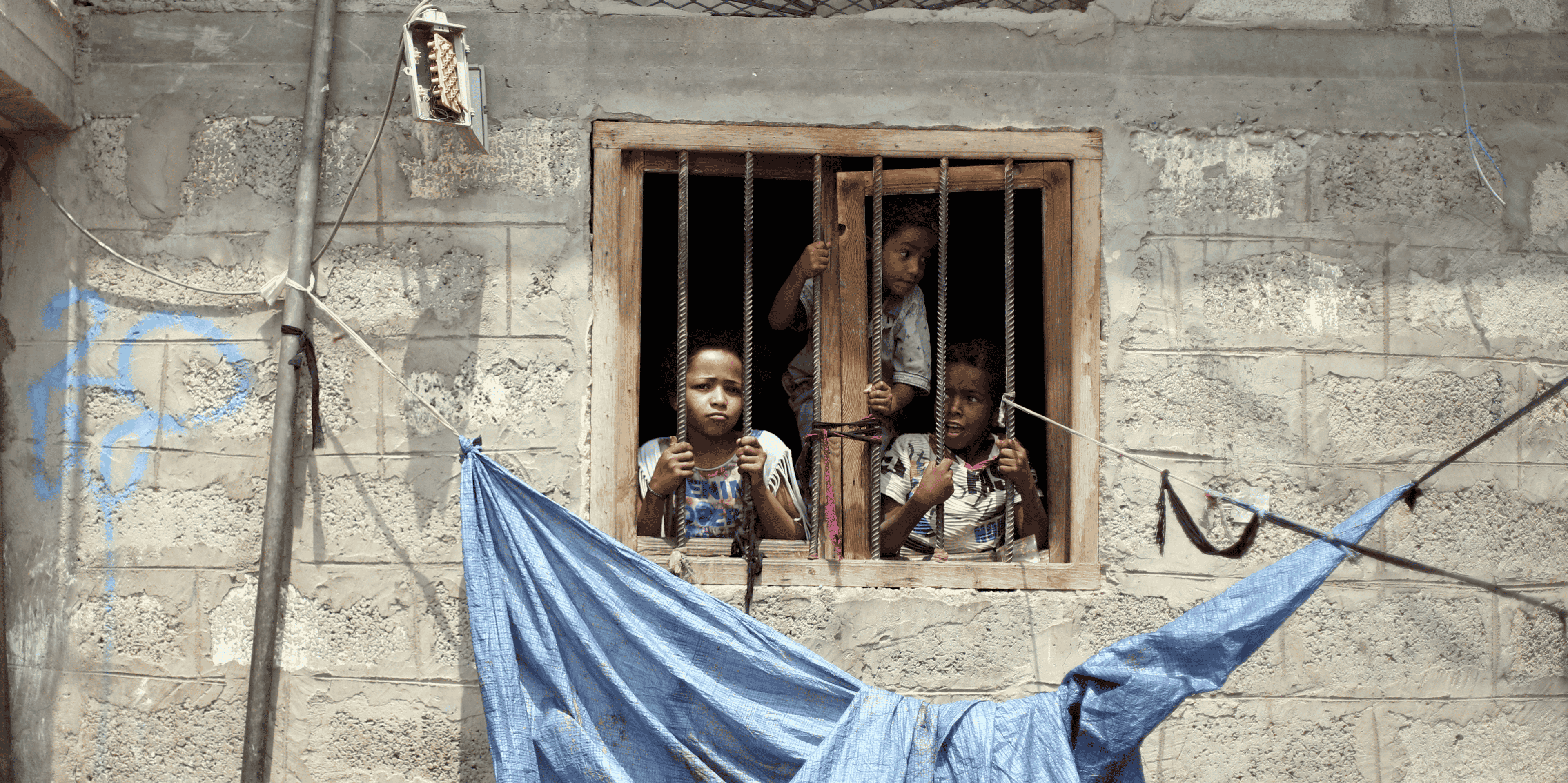 Yémen : des enfants de la communauté Muhamasheen regardent depuis la fenêtre de leur maison à Sanaa