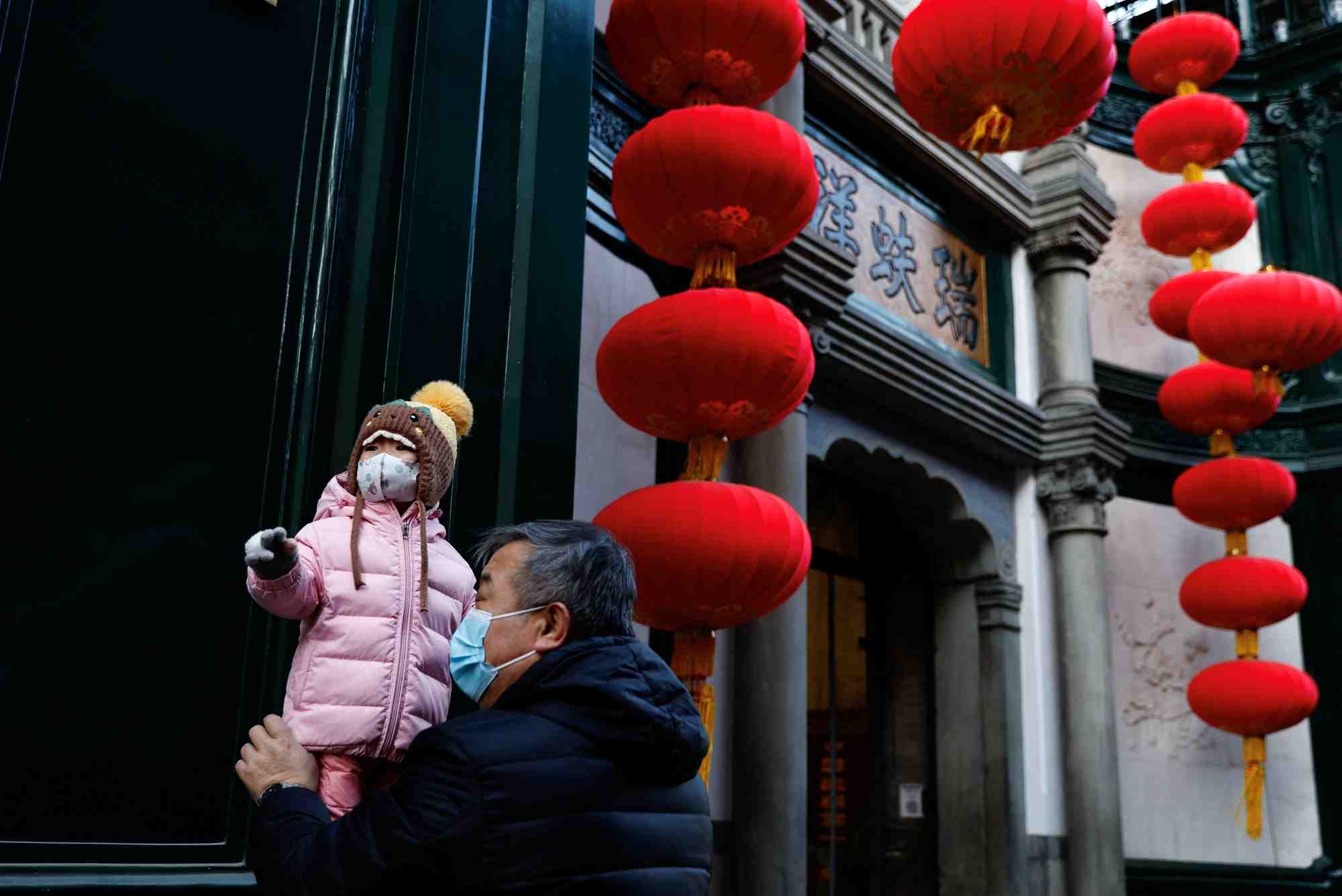 Un homme avec un enfant pres de lanternes decorant un magasin a l'approche du nouvel an lunaire chinois, a pekin