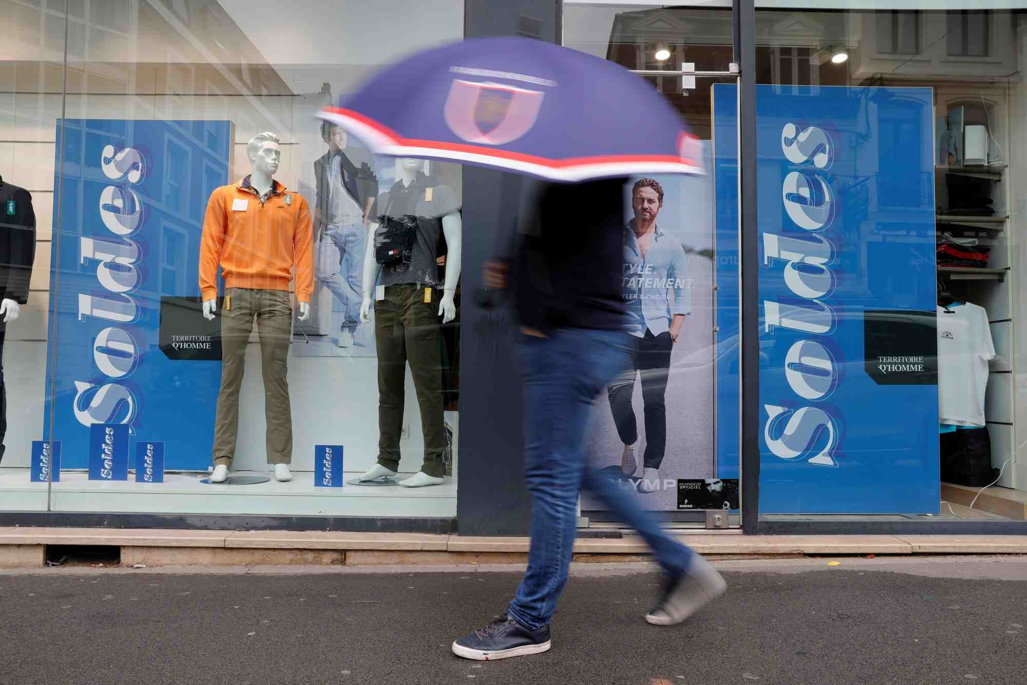Un homme passe devant une boutique de vetements a cambrai
