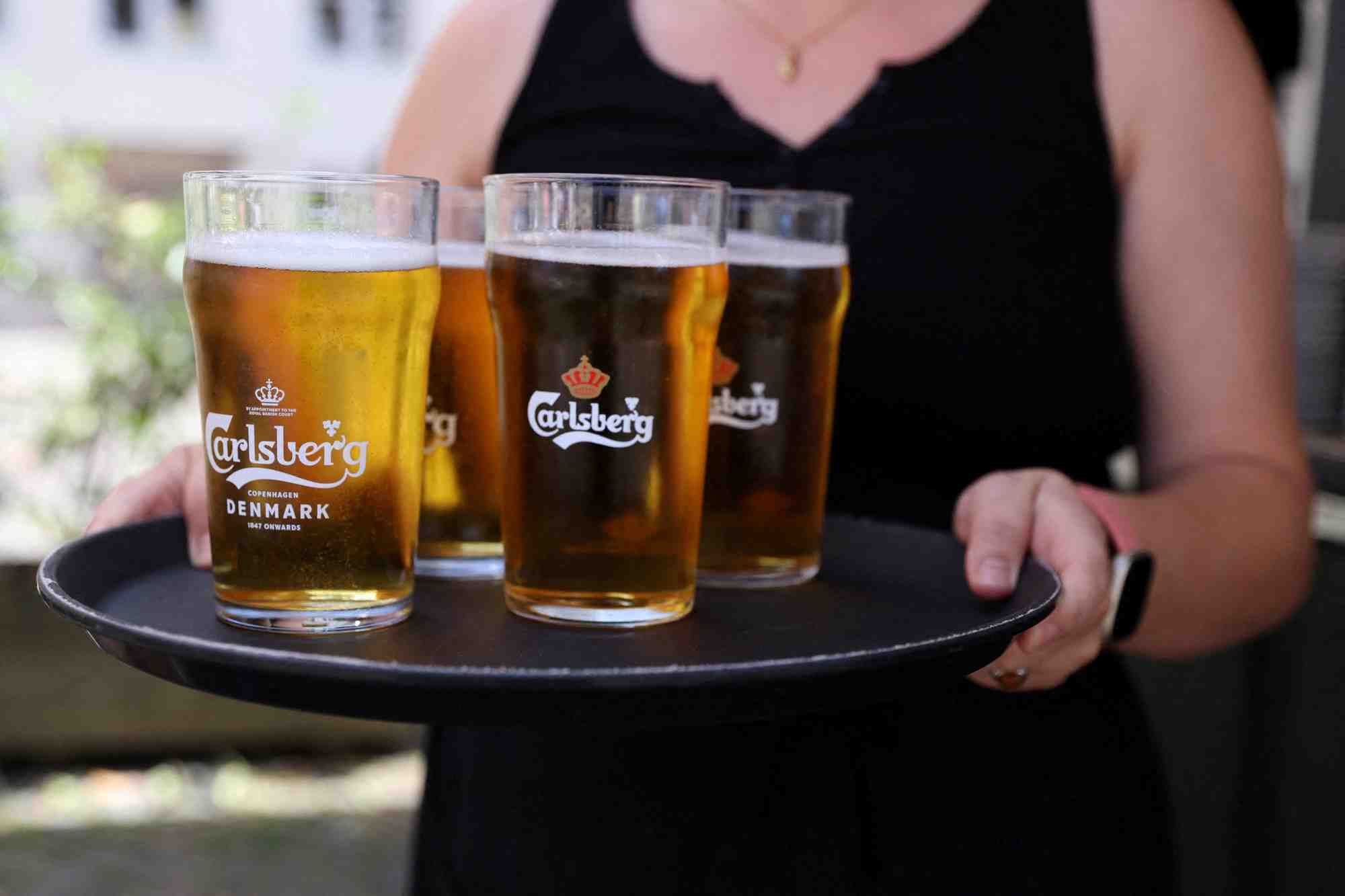 Un employe de bar porte un plateau de biere carlsberg a copenhague.