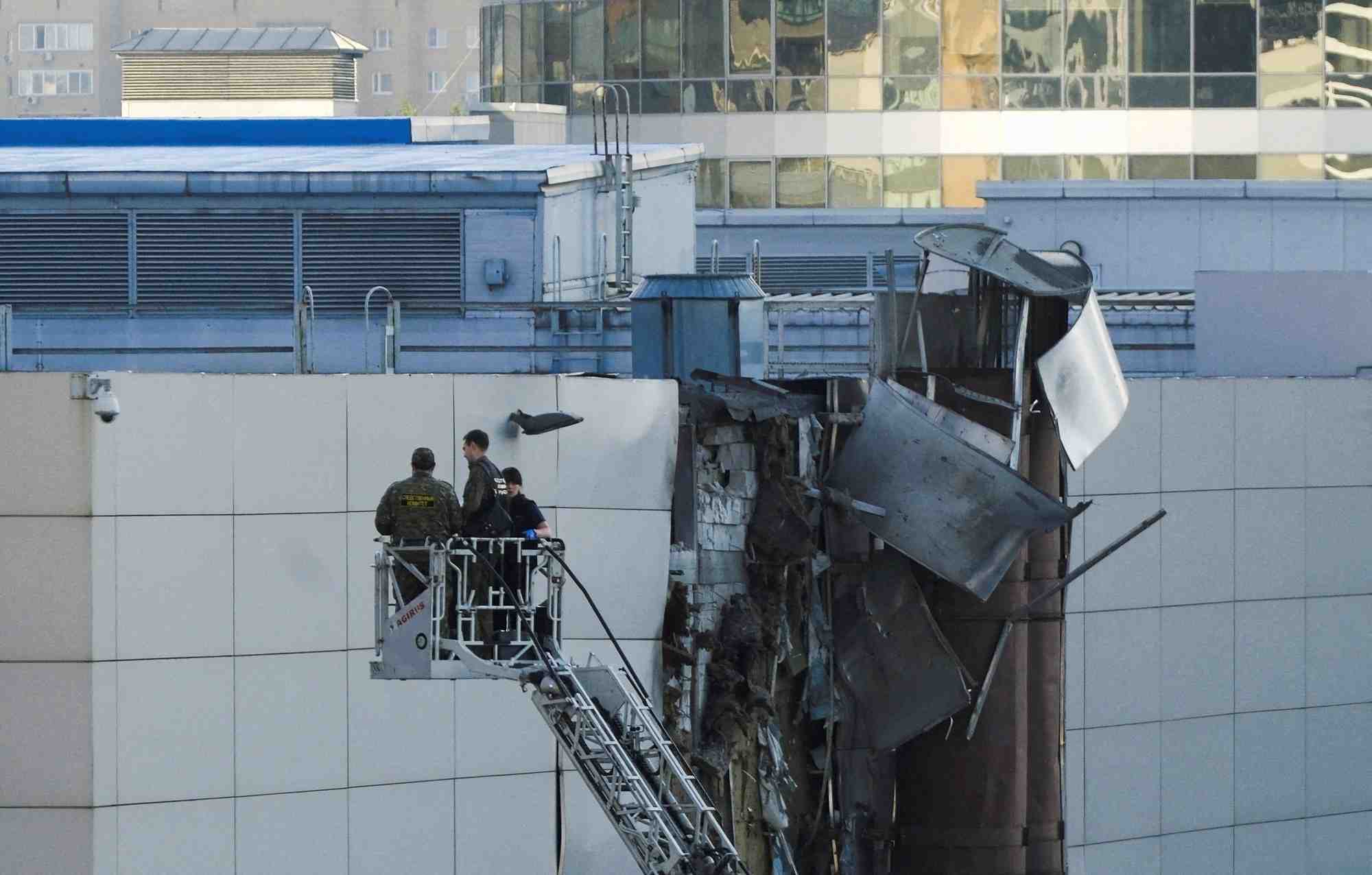 Des enqueteurs travaillent pres d'un toit endommage a la suite d'un drone ukrainien abattu a moscou