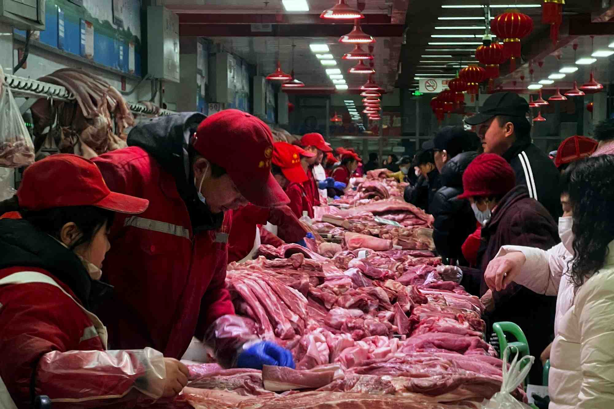 Des vendeurs de porc s'occupent des clients dans un marche a pekin