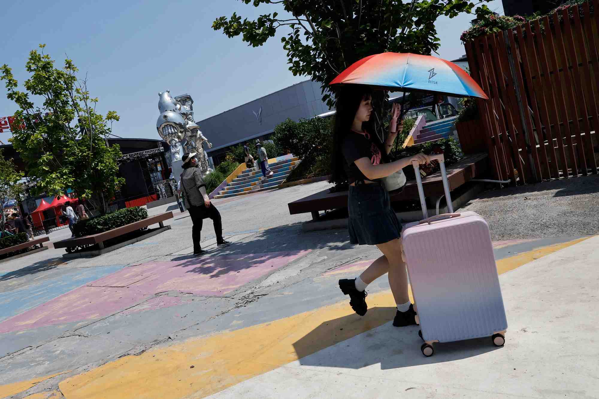 Une femme utilise un parapluie pour se proteger du soleil dans le cadre d'une alerte rouge a la canicule a pekin, en chine