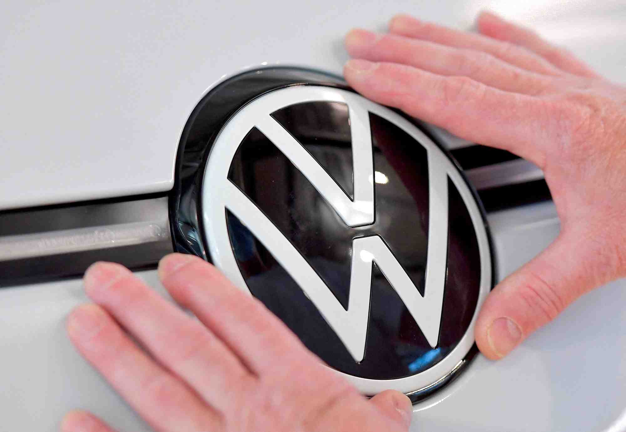 Photo d'archives: un technicien attache un panneau vw dans la chaine de montage de la voiture electrique id. 3 du constructeur automobile allemand volkswagen