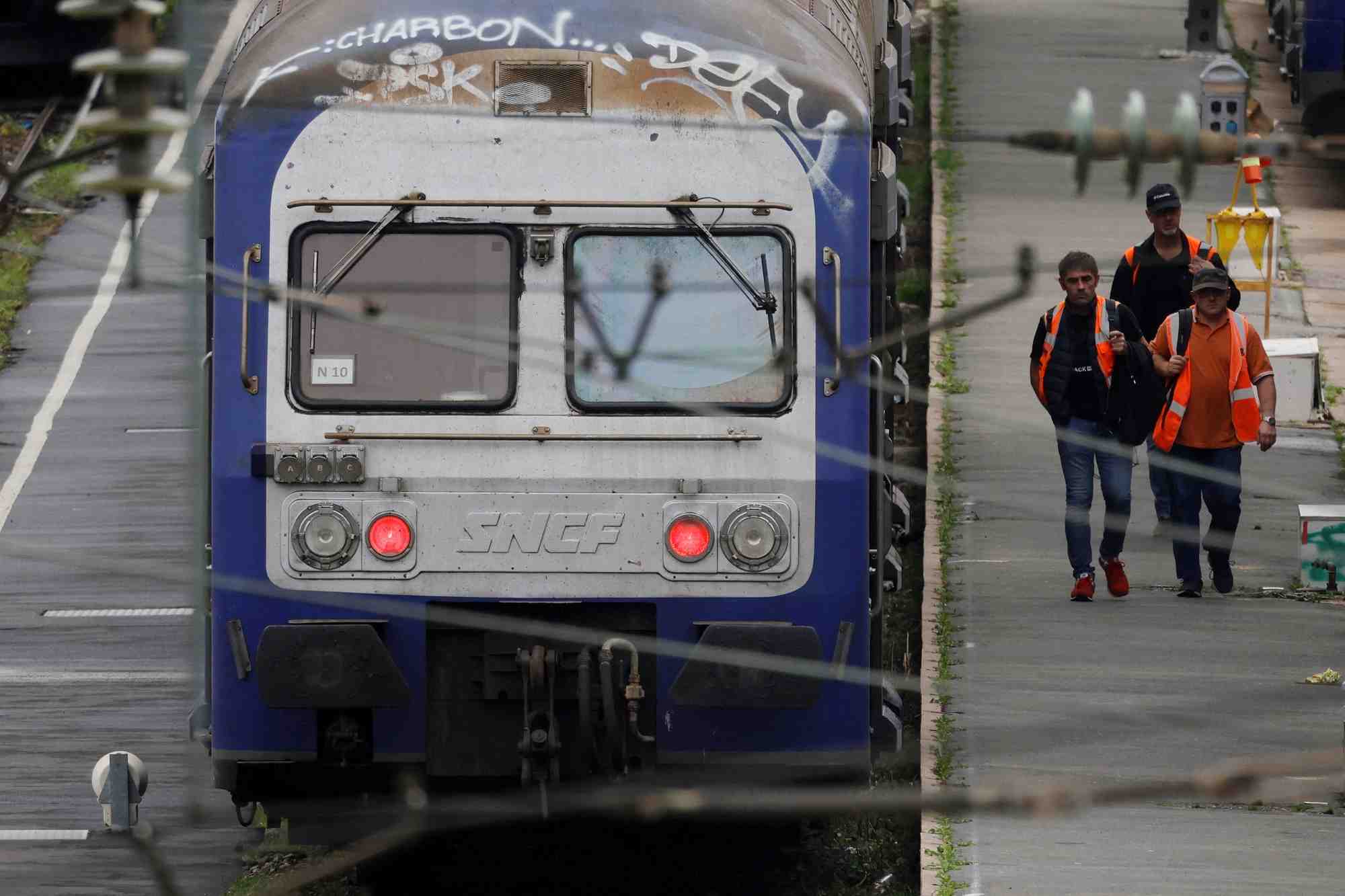 Des ouvriers passent devant des trains regionaux ter au depot sncf d'hellemmes-lille