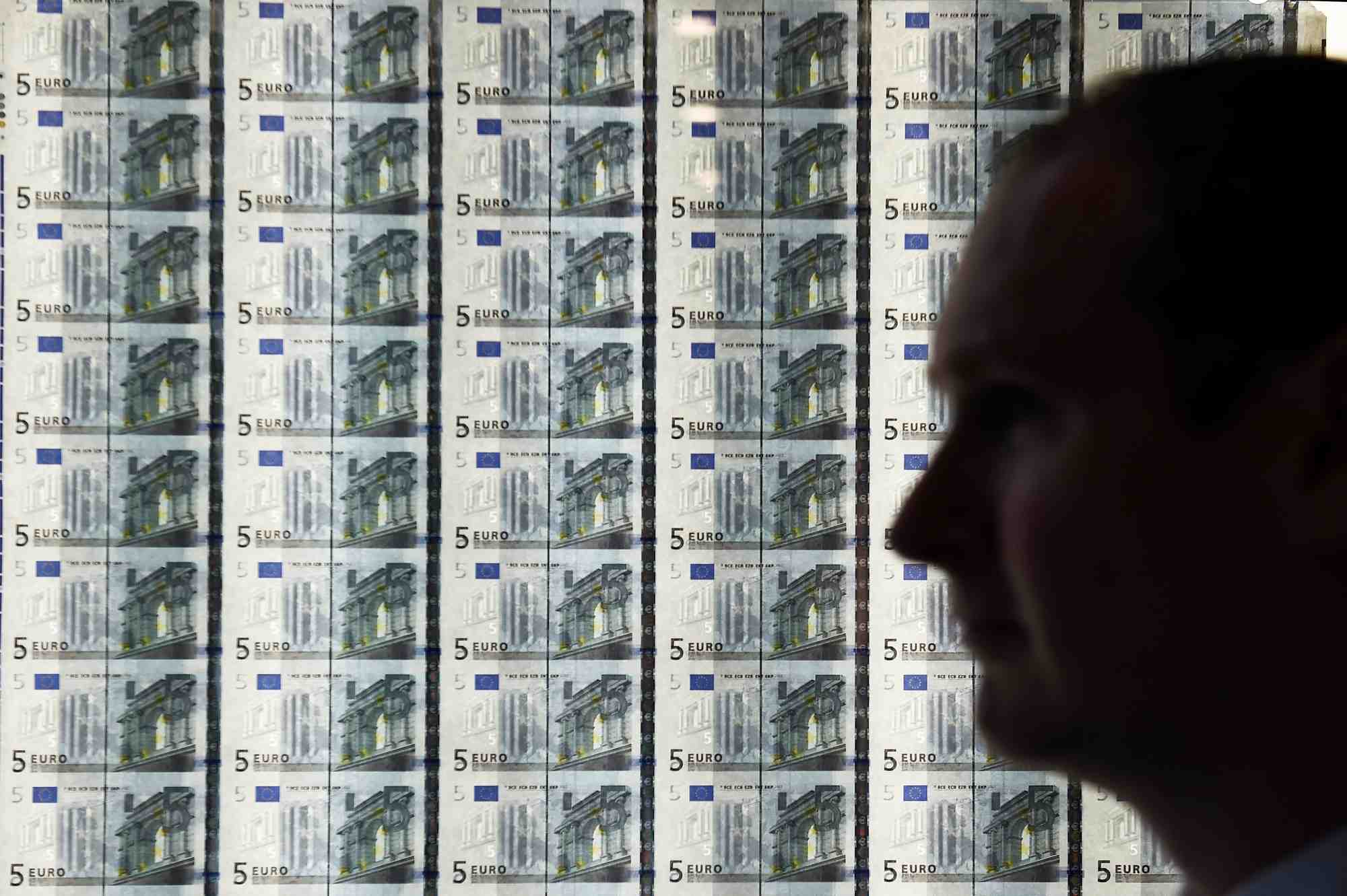 Un homme est vu devant une feuille de billets de cinq euros