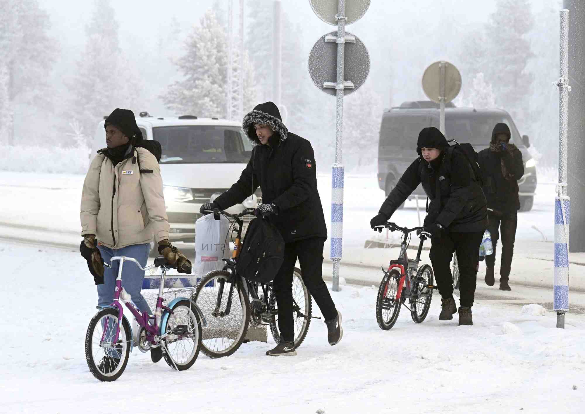 Des migrants marchent avec des velos au poste frontiere entre la finlande et la russie, a salla