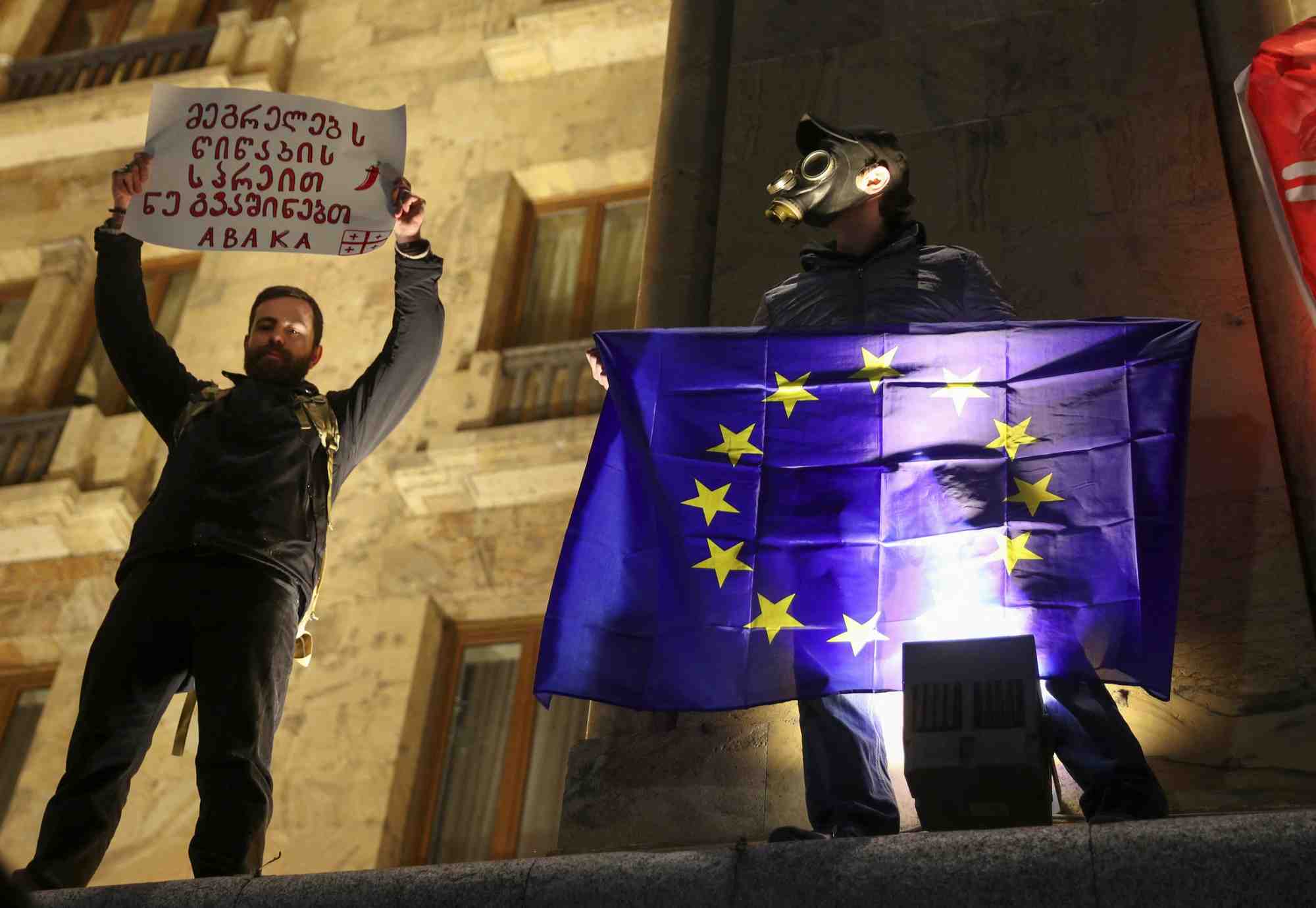 Des activistes se tiennent sur un parapet devant le batiment du parlement en georgie